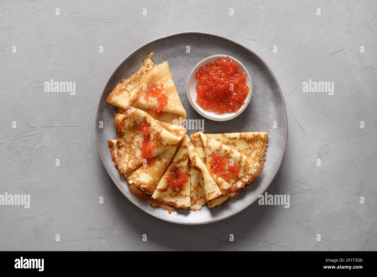 Russische dünne Pfannkuchen mit rotem Kaviar auf grauem Betongrund. Draufsicht. Traditionelle Religion Frühstück für nationale Feiertag Fasching. Maslenits Stockfoto