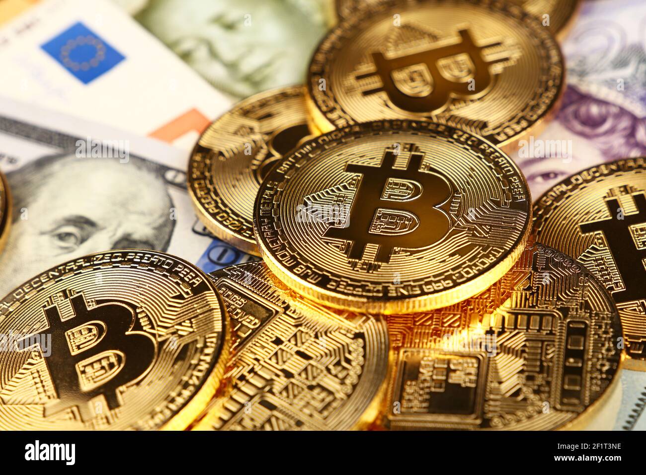 Close up Heap von golden Bitcoin physische Münzen, die auf Euro, Dollar, Pfund und Yuan Papier Banknoten der Hintergrund, Hohe Betrachtungswinkel, selektive Stockfoto