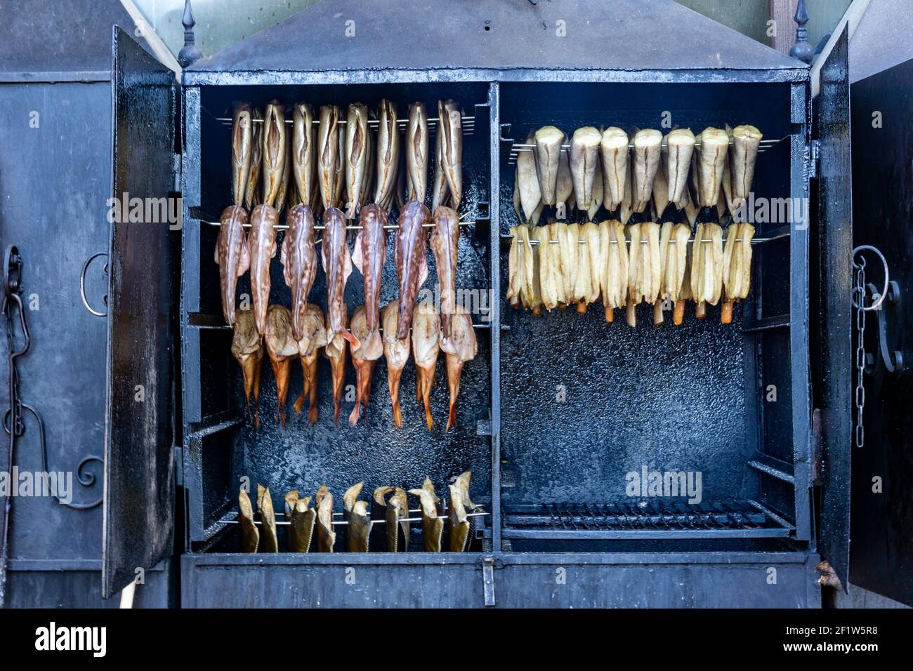 Eine Nahaufnahme von Rauchern oder Rösteröfen mit verschiedenen Arten von Fisch, der geraucht wird Stockfoto