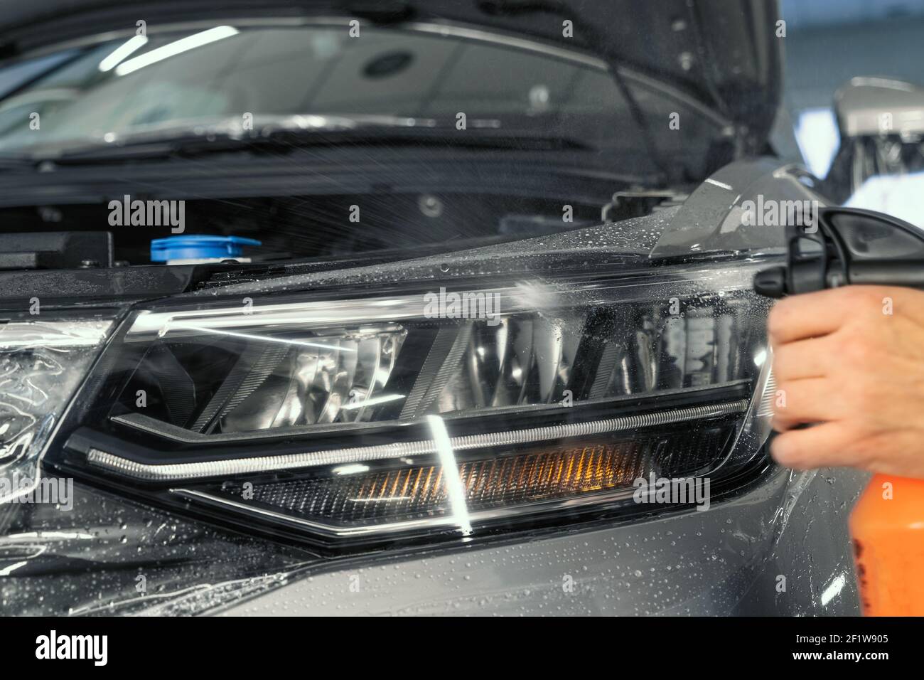 PPF-Einbau am Autoscheinwerfer. Lackschutzfolie ist eine schützende Polyurethan-Beschichtung für die Lackierung im Auto. Stockfoto