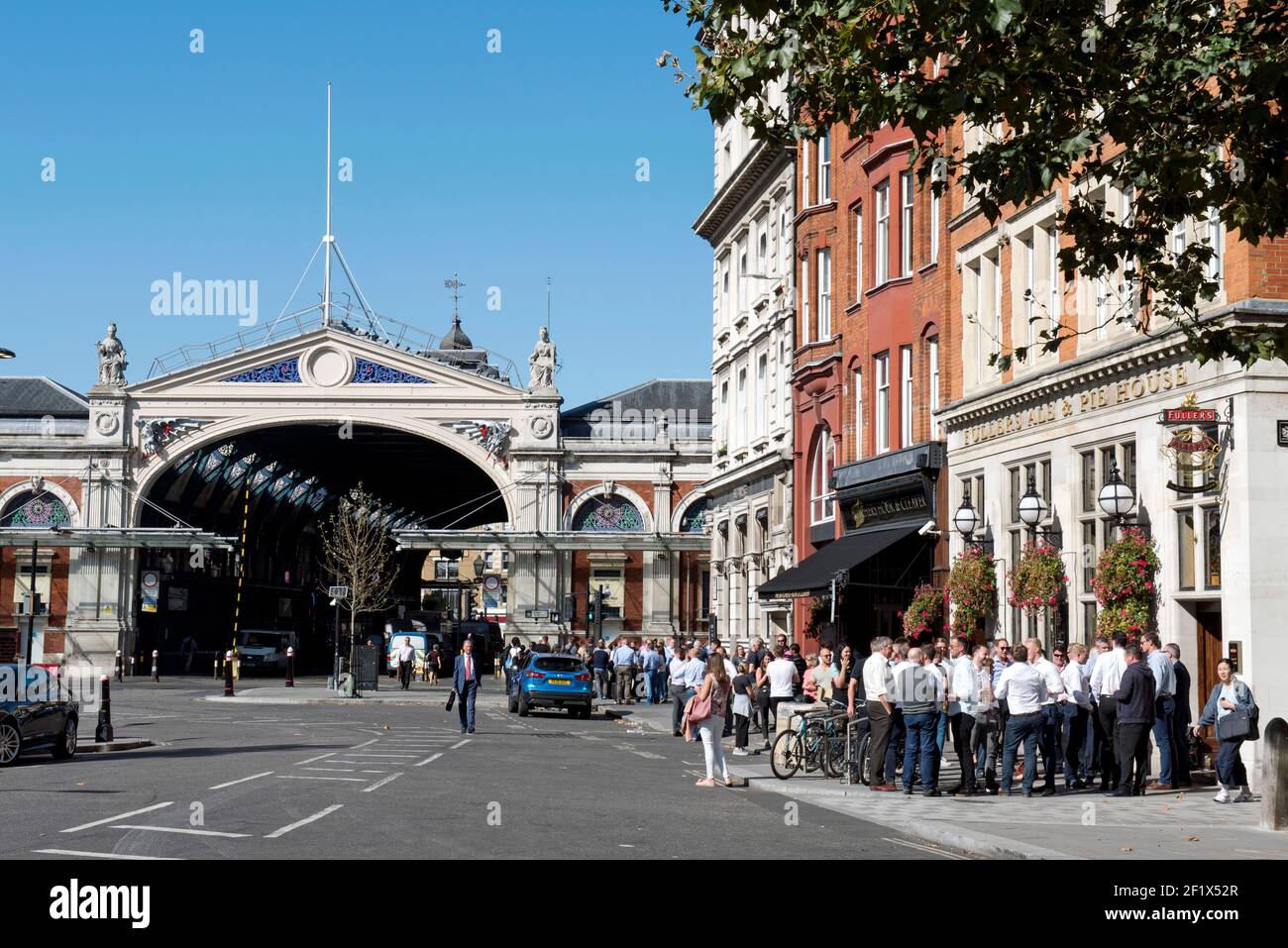 Die Leute trinken außerhalb Fullers Ale & Pie House Pub oder öffentlichen Haus mit Markt Gebäude im Hintergrund West Smithfield, London Stockfoto