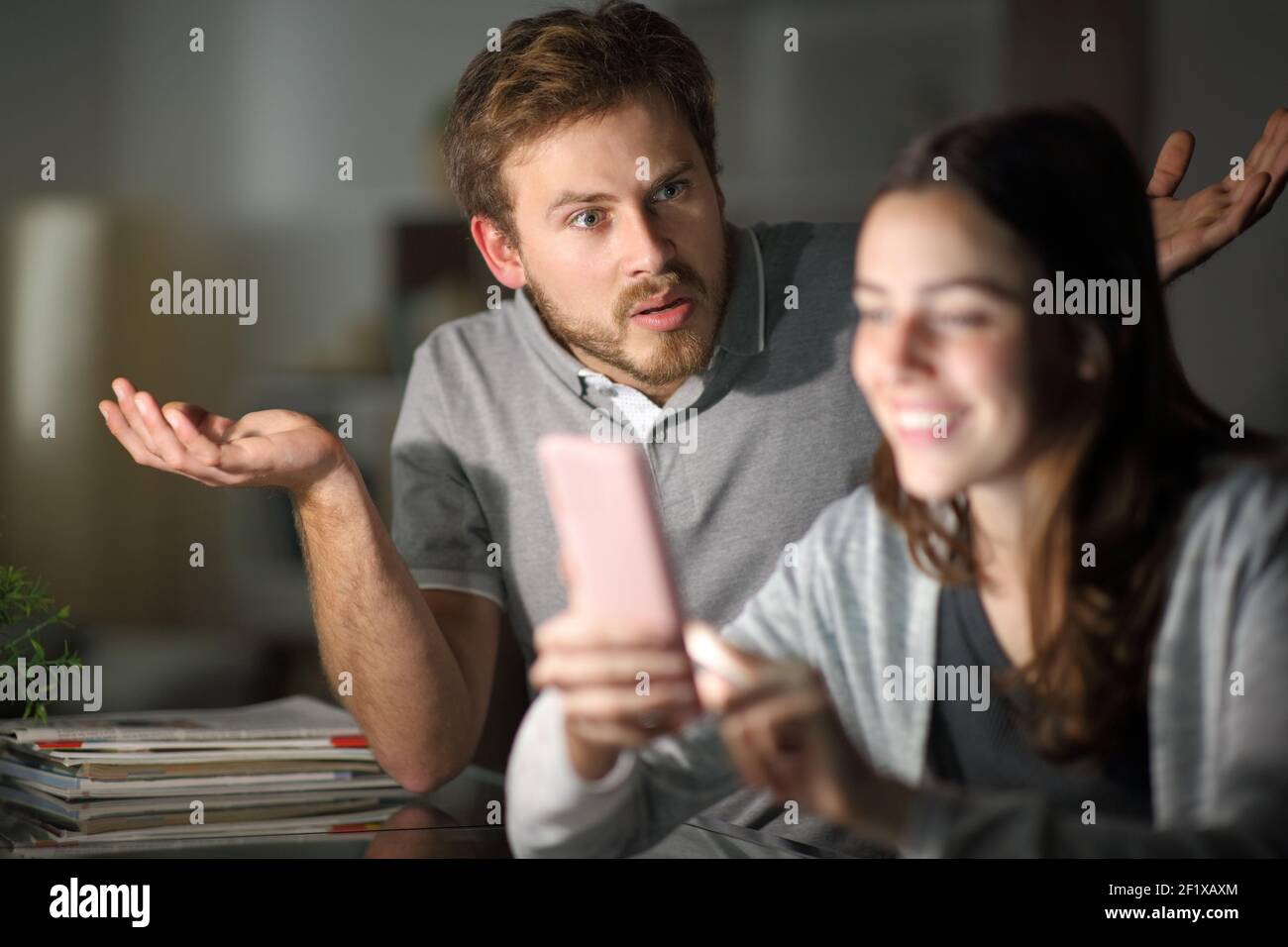 Ehefrau mit Smartphone ignoriert ihren Mann in der Nacht zu Hause Stockfoto