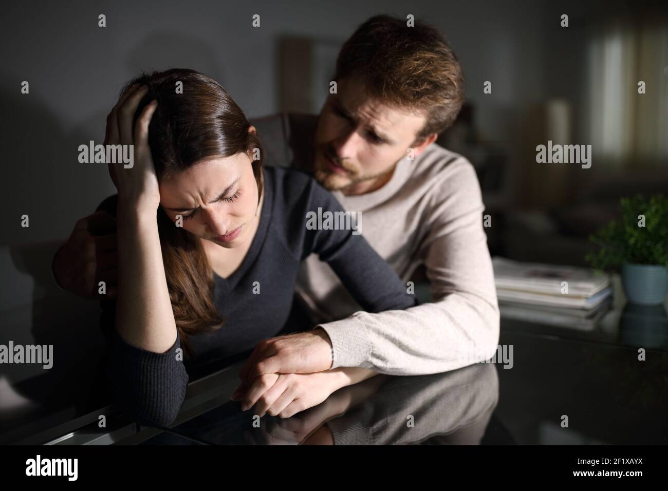 Traurige Frau und Ehemann trösten sie im Wohnzimmer In der Nacht zu Hause Stockfoto