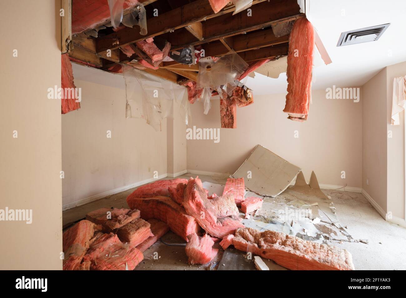 Eine Decke stürzte ein, und die Isolierung fiel in einem verlassenen Haus heraus. Stockfoto
