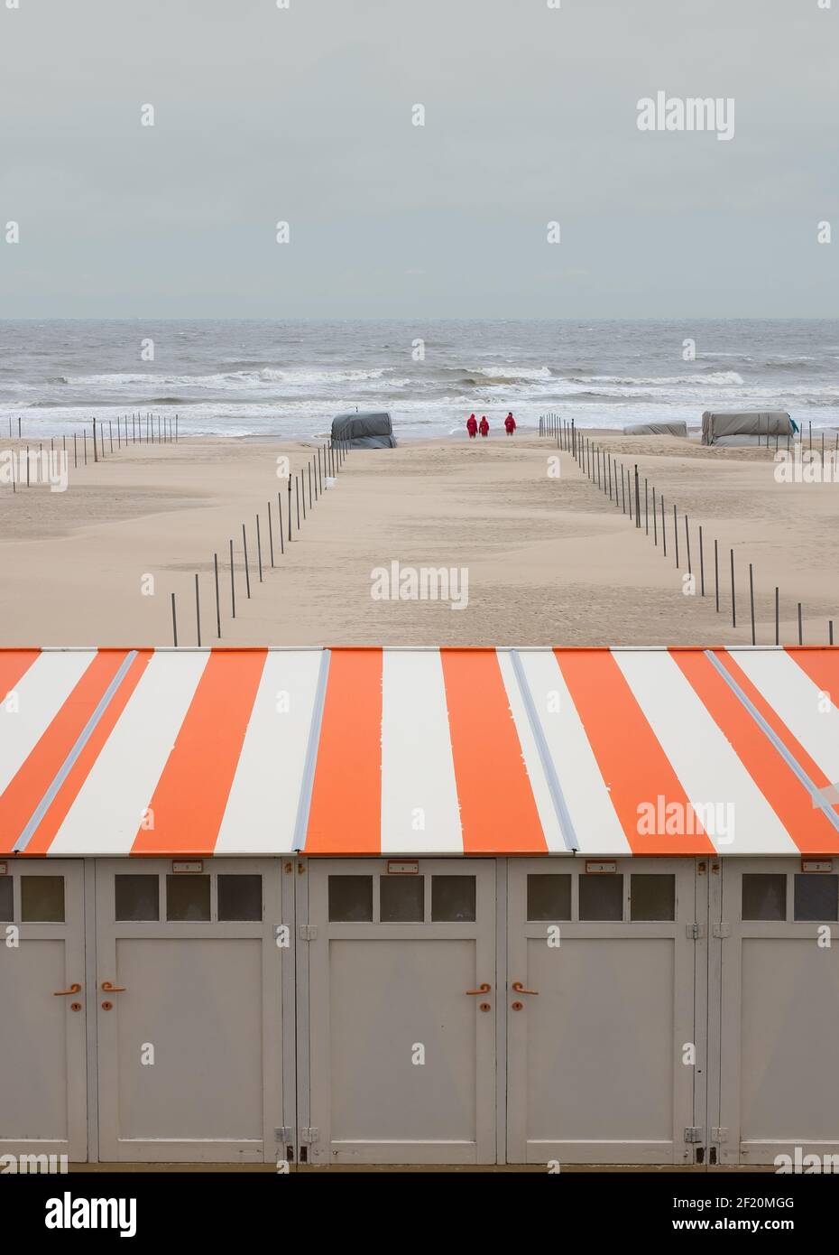 Gestreifte Strandhütten in einer Reihe auf dem belgischen Norden Meeresküste gegen bewölkten Himmel Stockfoto