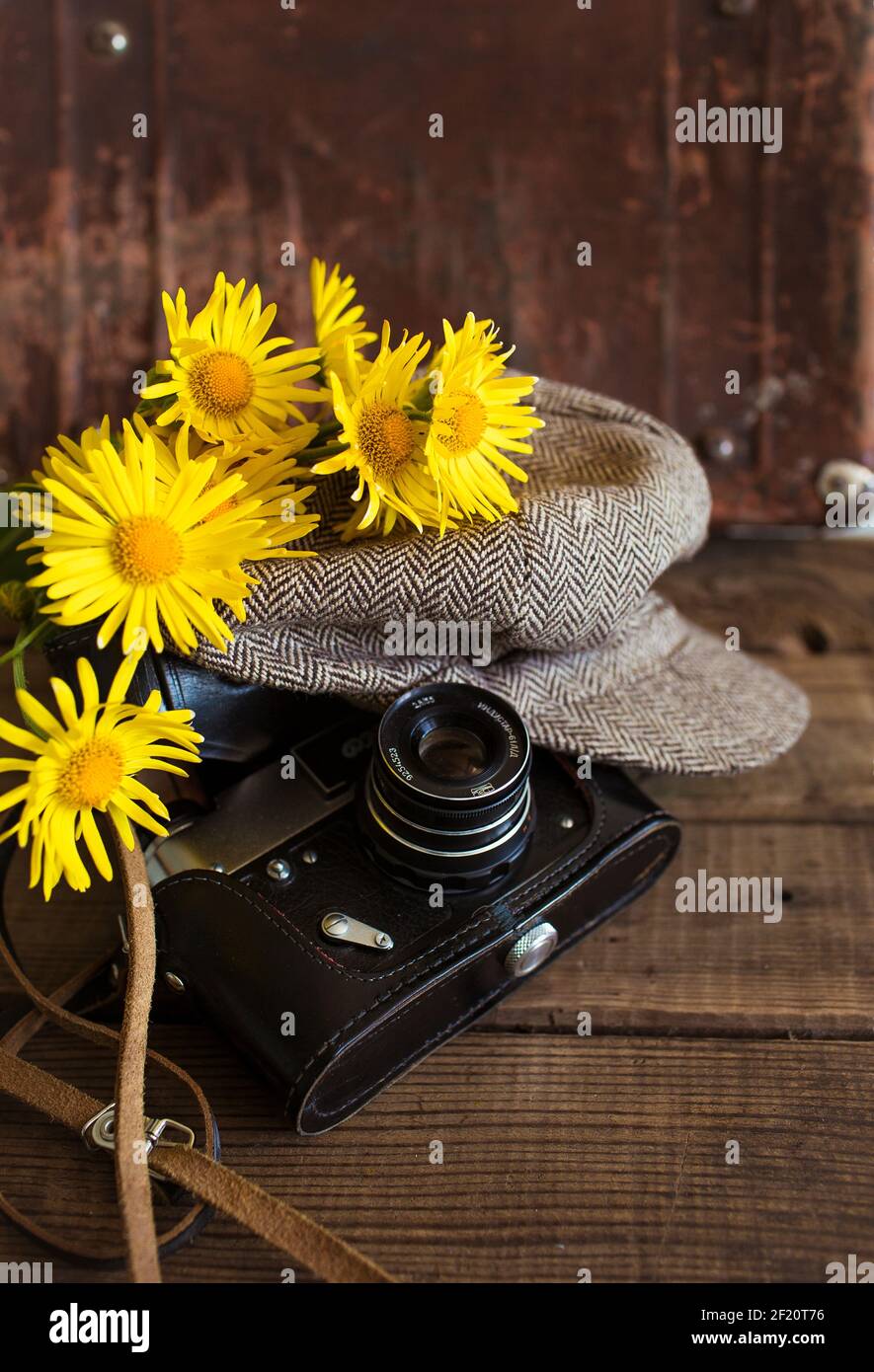 Nahaufnahme eines alten Kamera Vintage Hut und ein Strauß von gelben Blumen auf einem hölzernen Hintergrund Stockfoto