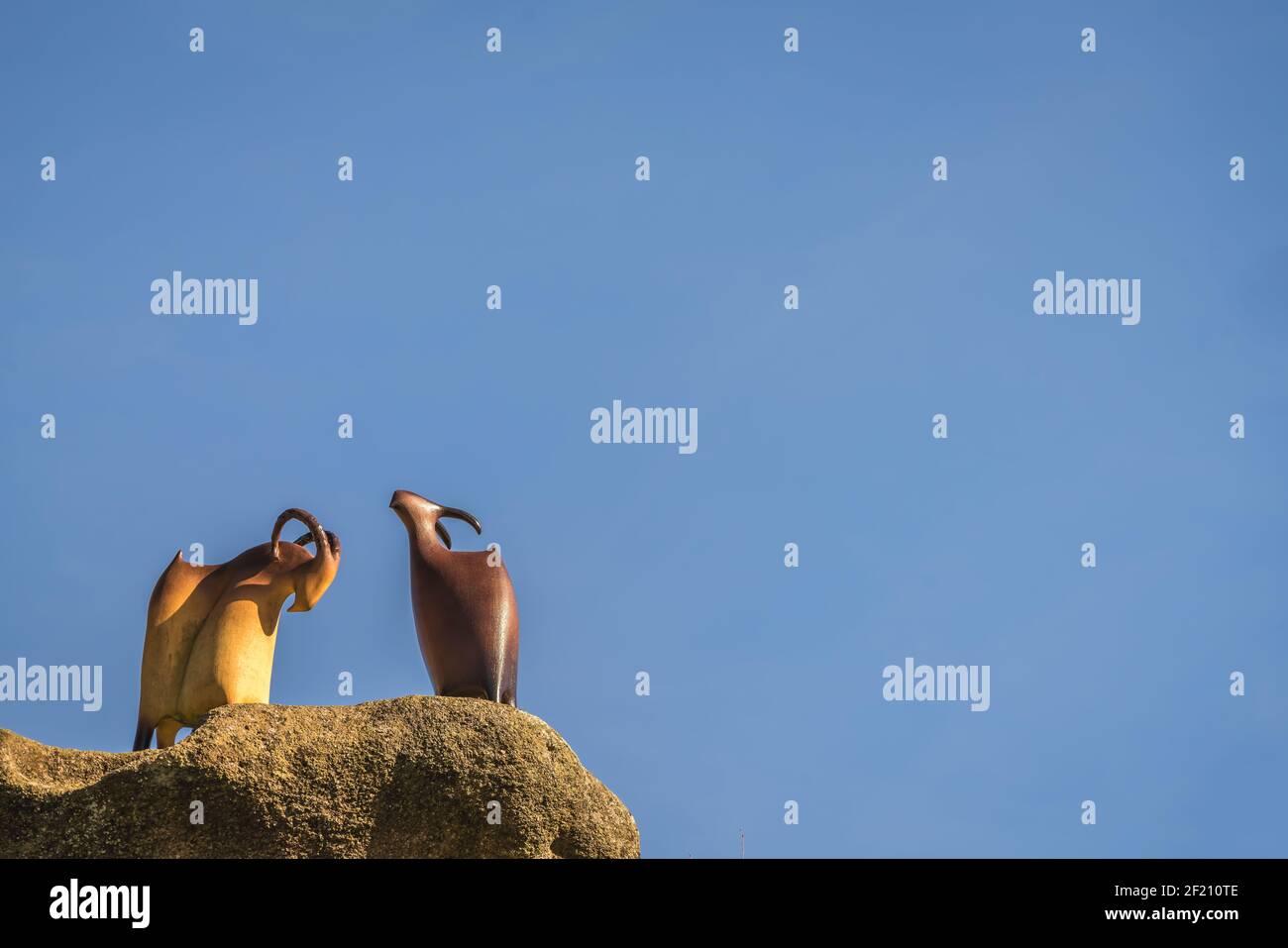 Zwei Ziegenskulpturen auf einem Felsen Stockfoto
