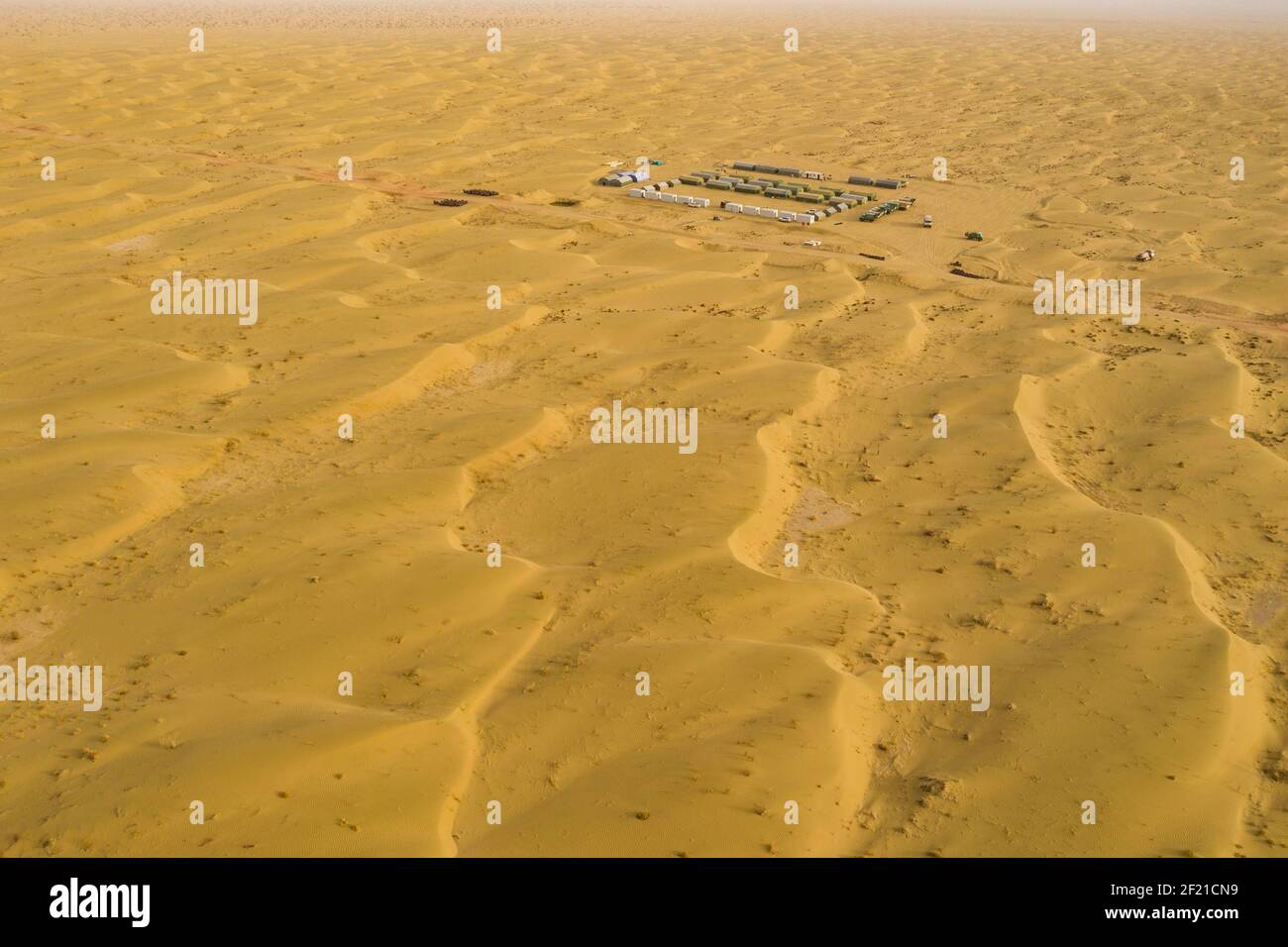 (210310) --URUMQI, 10. März 2021 (Xinhua) -- Luftbild zeigt den Lagerplatz des geophysikalischen Vermessungsteams in der Taklimakan-Wüste, nordwestlich der Autonomen Region Xinjiang Uygur in China, 25. Februar 2021. Die Taklimakan-Wüste im Tarim-Becken der Autonomen Region Xinjiang Uygur im Nordwesten Chinas ist eine der größten petroliferösen Regionen Chinas und aufgrund ihrer rauen Bodenbedingungen und der komplizierten unterirdischen Bedingungen eine der schwierigsten zu erkunden. Die Erkundung der Öl- und Gasressourcen erfordert mehrere Prozesse, einschließlich der Durchführung geophysikalischer Untersuchungen, um seismische Daten zu sammeln Stockfoto
