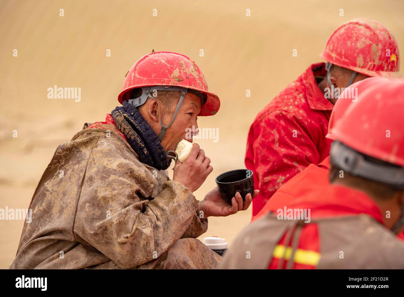 (210310) --URUMQI, 10. März 2021 (Xinhua) -- Arbeiter des geophysikalischen Vermessungsteams essen am 25. Februar 2021 in der Taklimakan-Wüste im Nordwesten Chinas, der Autonomen Region Xinjiang Uygur. Die Taklimakan-Wüste im Tarim-Becken der Autonomen Region Xinjiang Uygur im Nordwesten Chinas ist eine der größten petroliferösen Regionen Chinas und aufgrund ihrer rauen Bodenbedingungen und der komplizierten unterirdischen Bedingungen eine der schwierigsten zu erkunden. Die Erkundung der Öl- und Gasressourcen erfordert mehrere Prozesse, einschließlich der Durchführung geophysikalischer Untersuchungen, um seismische Daten zu sammeln, um eine Soli zu legen Stockfoto
