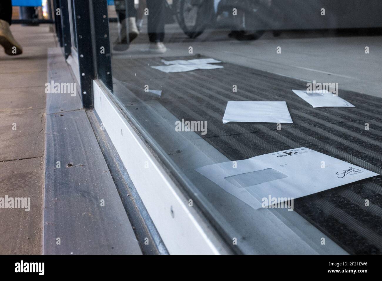 Nicht gesammelte Briefe und Post hinter einer Glastür auf der Southbank, London, Großbritannien Stockfoto