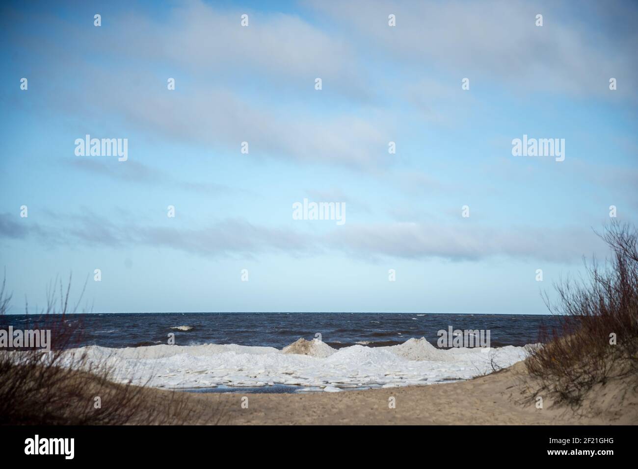 Meeresküste mit blauem Himmel und gewaschenen Eisstücken an der Küste. Frühlingslandschaft Stockfoto