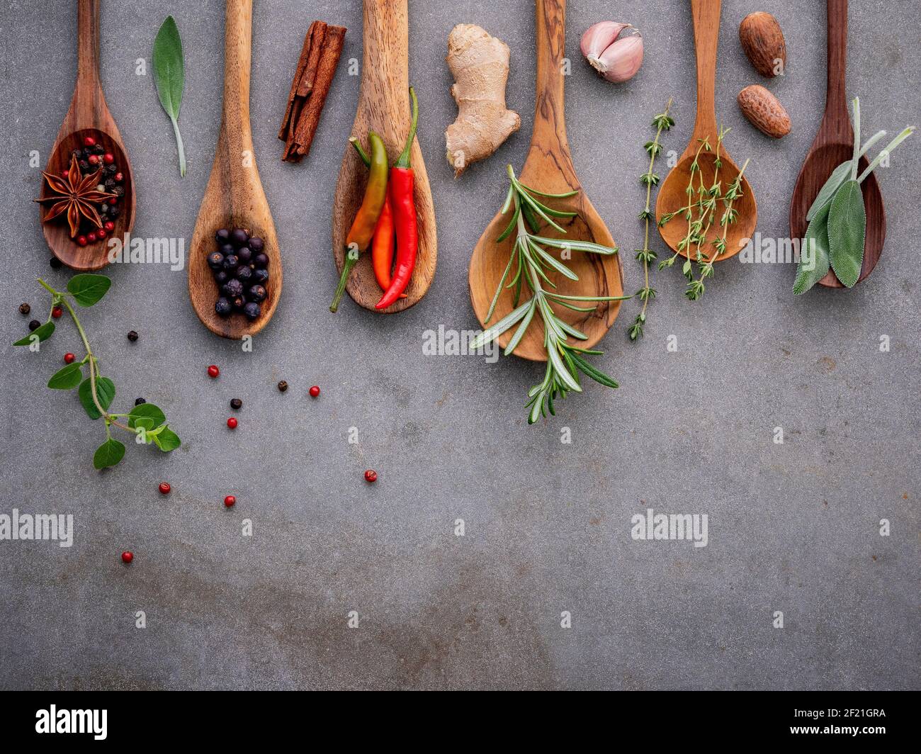 Verschiedene Gewürze und Kräuter in der Kochlöffel. Flach Gewürze Zutaten Chili, Pfeffer, rosemarry, Thymian, Sternanis, Salbei und Basilikum Stockfoto