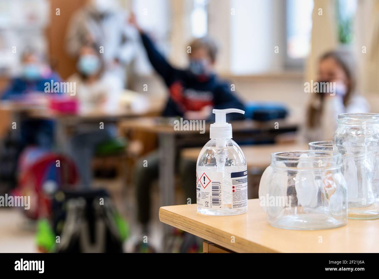München, Deutschland. März 2021, 10th. Ein Desinfektionsgel steht im Klassenzimmer einer vierten Klasse an einer Grundschule, während im Hintergrund Schüler an der Lektion teilnehmen. Der bayerische Bildungsminister Piazolo (Freie Wähler) und der bayerische Gesundheitsminister Holetschek (CSU) besuchen die Grundschule, um sich über die Umsetzung der Corona-Teststrategie zu überzeugen. Quelle: Matthias Balk/dpa/Alamy Live News Stockfoto