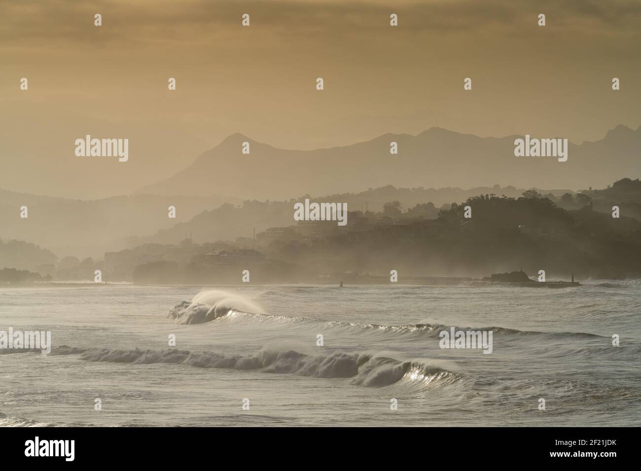 Eine Berglandschaft in Silhouette mit Strand und Wellen brechen Im Vordergrund Stockfoto