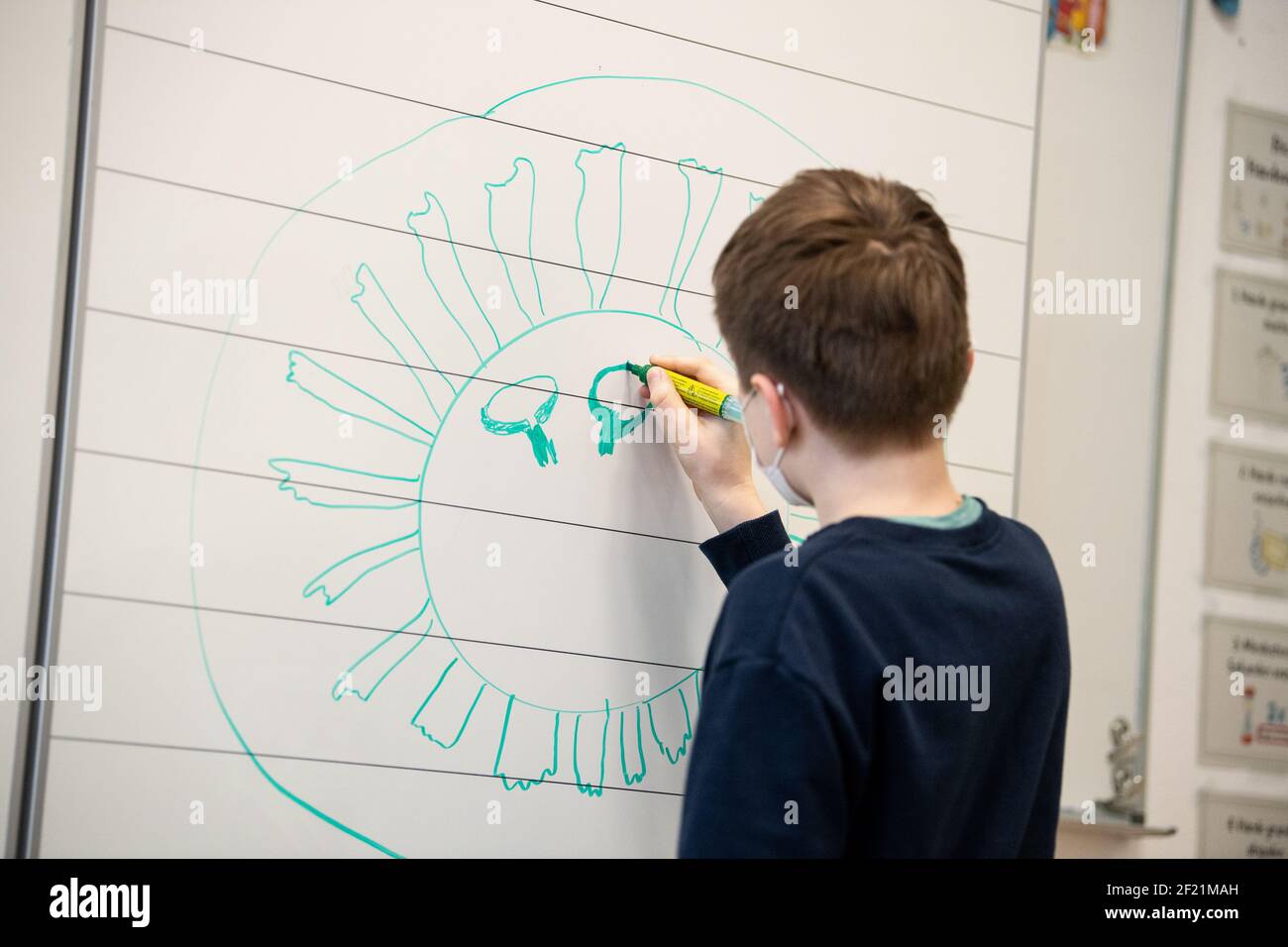 München, Deutschland. März 2021, 10th. Ein Schüler einer vierten Klasse einer Grundschule zieht einen Corona-Virus auf die Tafel. Der bayerische Bildungsminister Piazolo (Freie Wähler) und der bayerische Gesundheitsminister Holetschek (CSU) besuchten die Grundschule, um die Umsetzung der Corona-Teststrategie zu sehen. Quelle: Matthias Balk/dpa/Alamy Live News Stockfoto