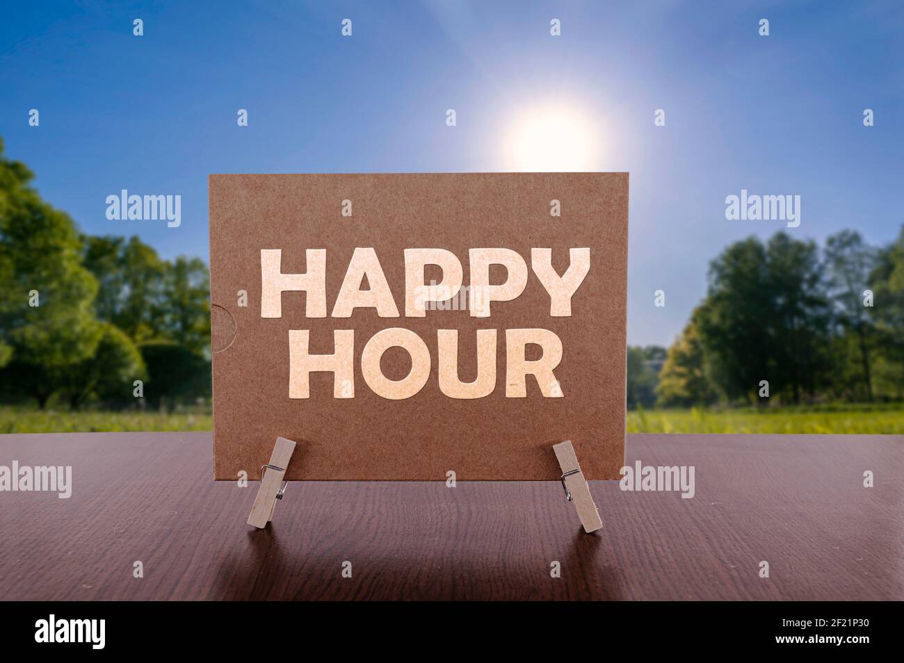 Happy Hour Text auf Karte auf dem Tisch mit sonnigen grünen Park Hintergrund. Stockfoto
