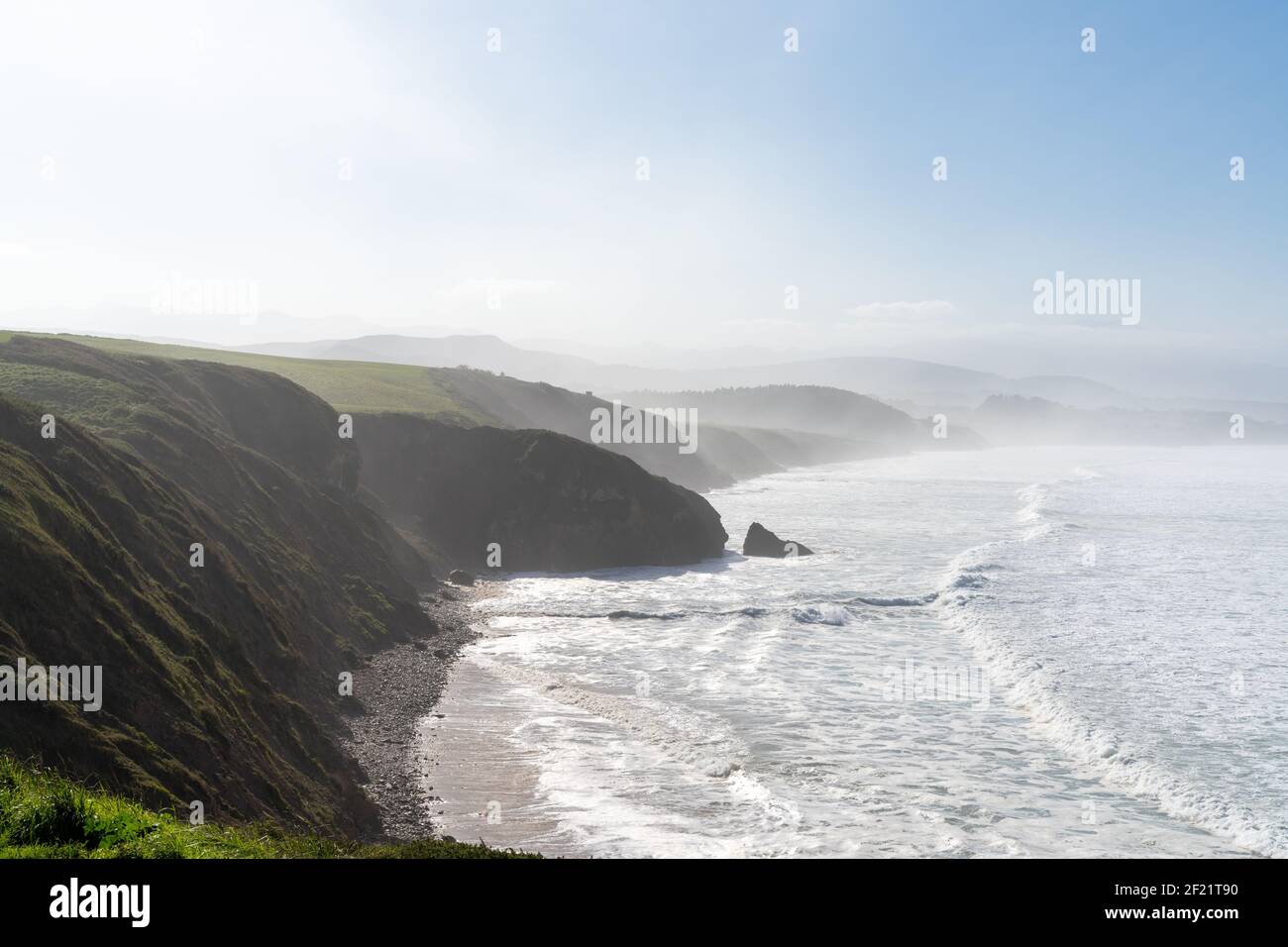 Hohe grüne grasbewachsene Klippen fallen hinunter zur Ozeanküste In Nordspanien Stockfoto