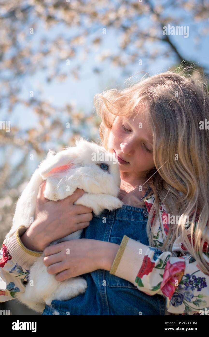 Liebenswert schöne Mädchen mit langen blonden Haaren umarmt weißen Ostern Kaninchentier Stockfoto