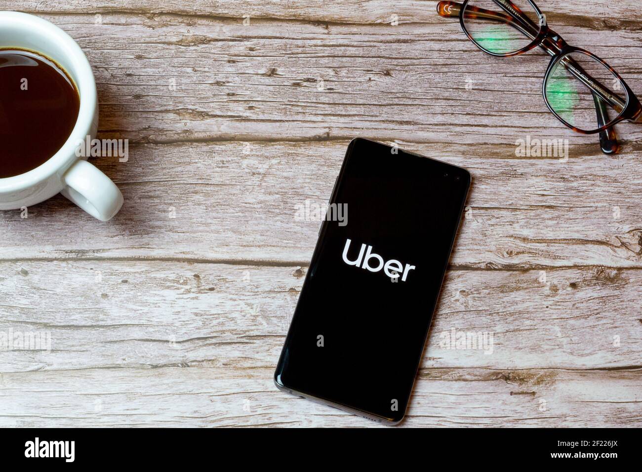 Ein Mobiltelefon oder Mobiltelefon auf einem Tisch Oder Schreibtisch mit der Uber App geöffnet und einen Kaffee Daneben Stockfoto