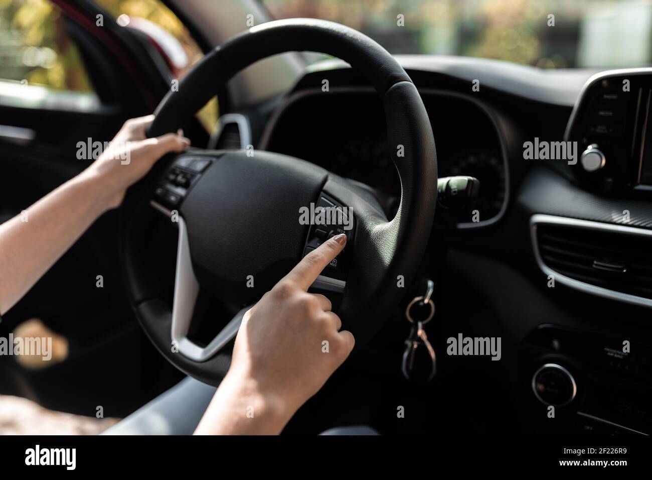 Innenansicht eines modernen Neuwagens. Hände einer jungen Frau am Steuer des Autos. Stockfoto
