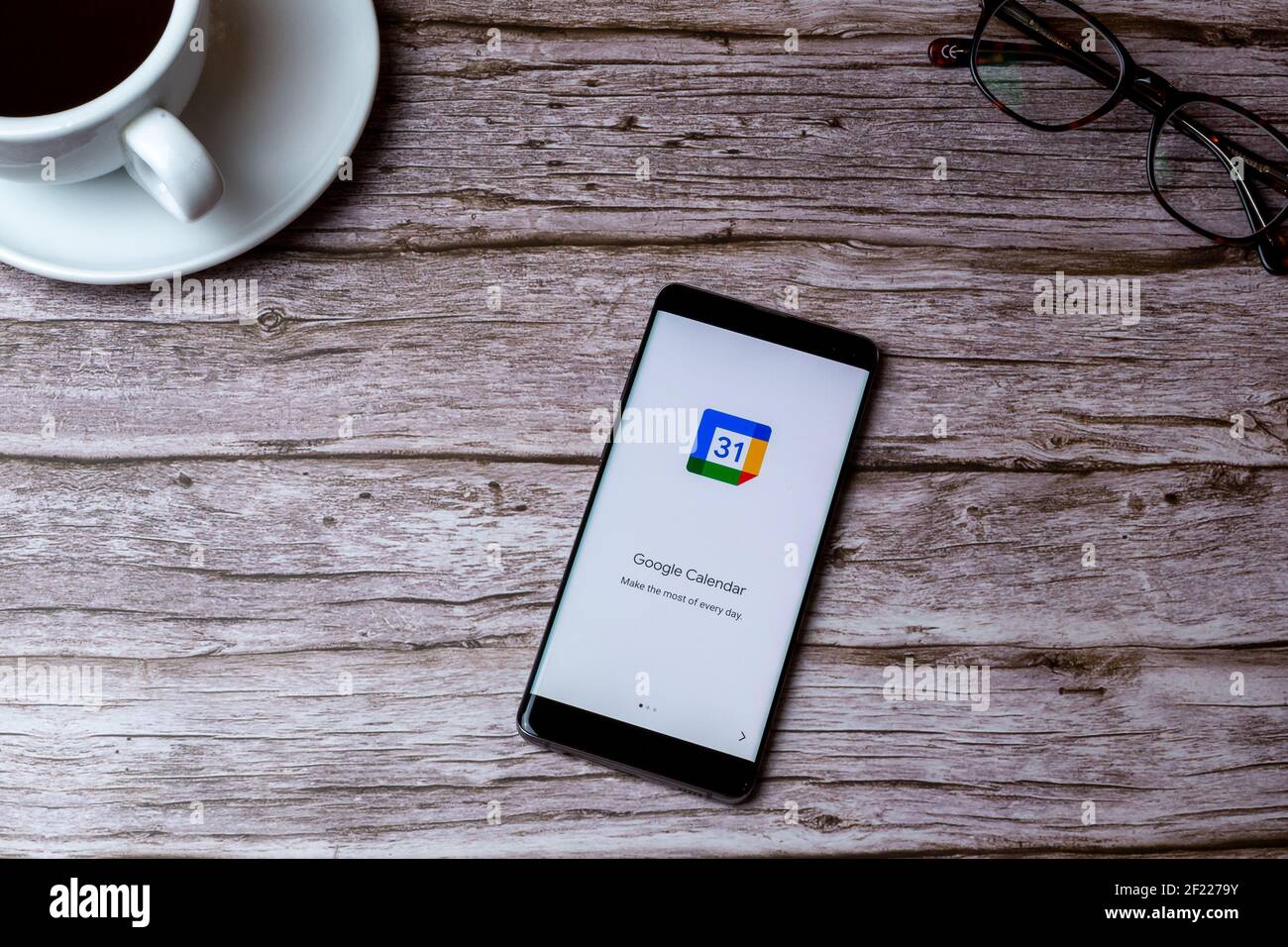 0A Handy oder Handy auf Holz gelegt Tisch oder Schreibtisch mit der Google Calendar App geöffnet Stockfoto