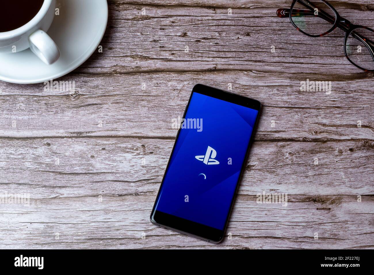Ein Handy oder Handy auf einem Holz gelegt Tisch oder Schreibtisch mit geöffneter sony PlayStation-App Stockfoto