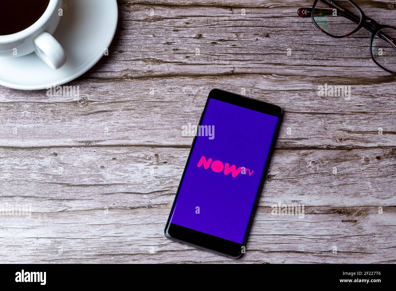 Ein Handy oder Handy auf einem Holz gelegt Tisch oder Schreibtisch mit geöffneter Now TV-App Stockfoto