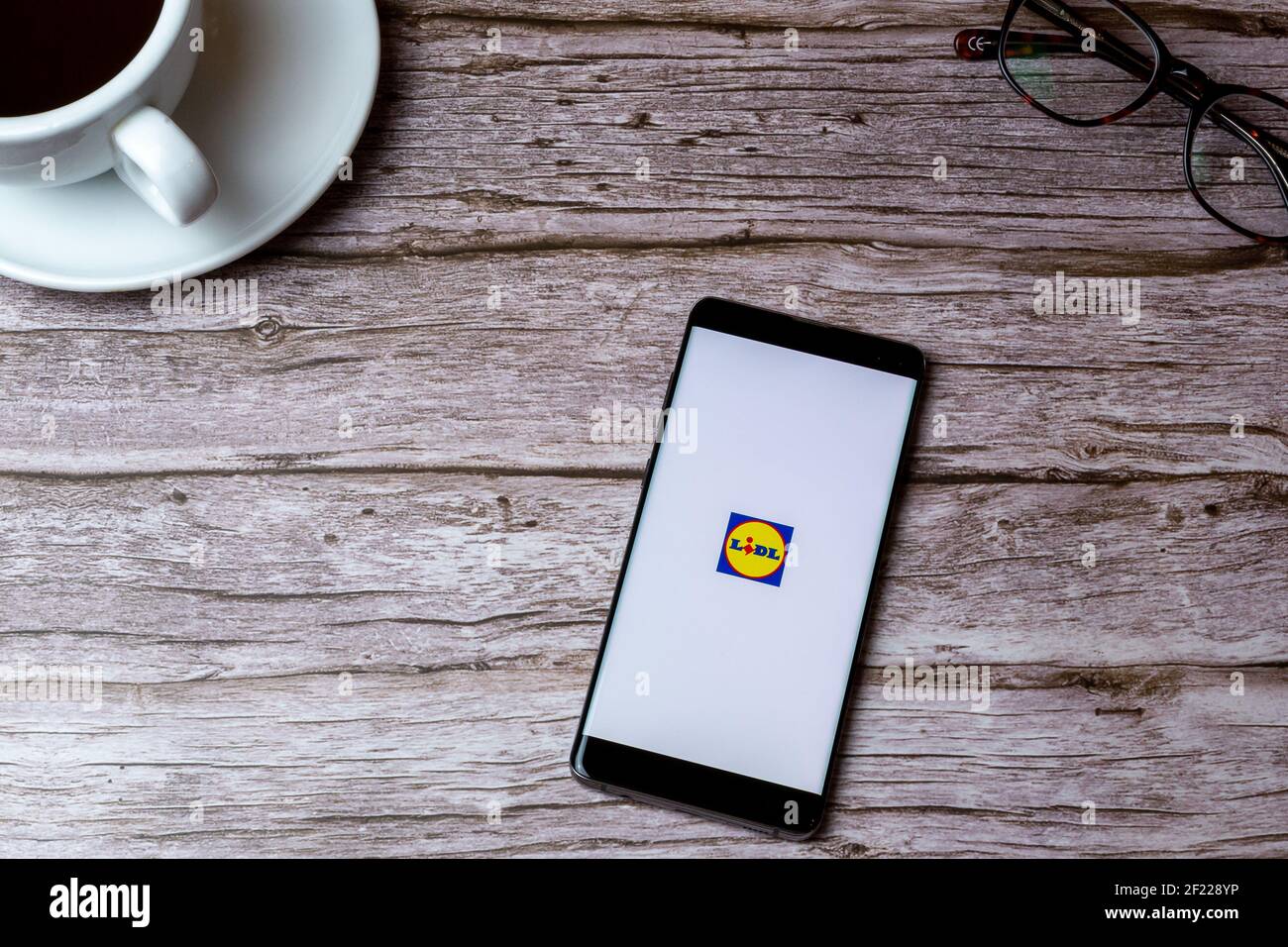 Ein Handy oder Handy auf einem Holz gelegt Tisch oder Schreibtisch mit der Lidl Supermarkt App geöffnet Stockfoto