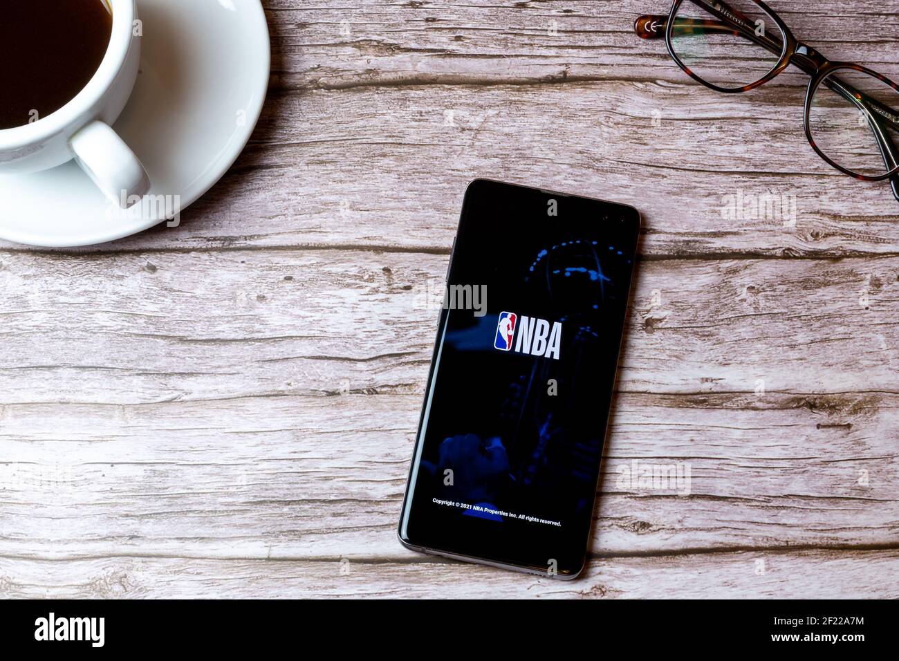 02-08-2021 Portsmouth, Hampshire, UK EIN Handy oder Handy auf einem Holztisch mit der NBA-App geöffnet neben einem Kaffee und Gläser gelegt Stockfoto