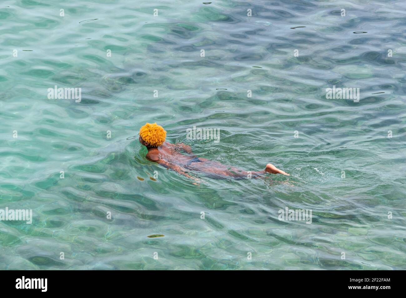 Schwarzer Mann schwimmt im türkisfarbenen Meerwasser. Stockfoto