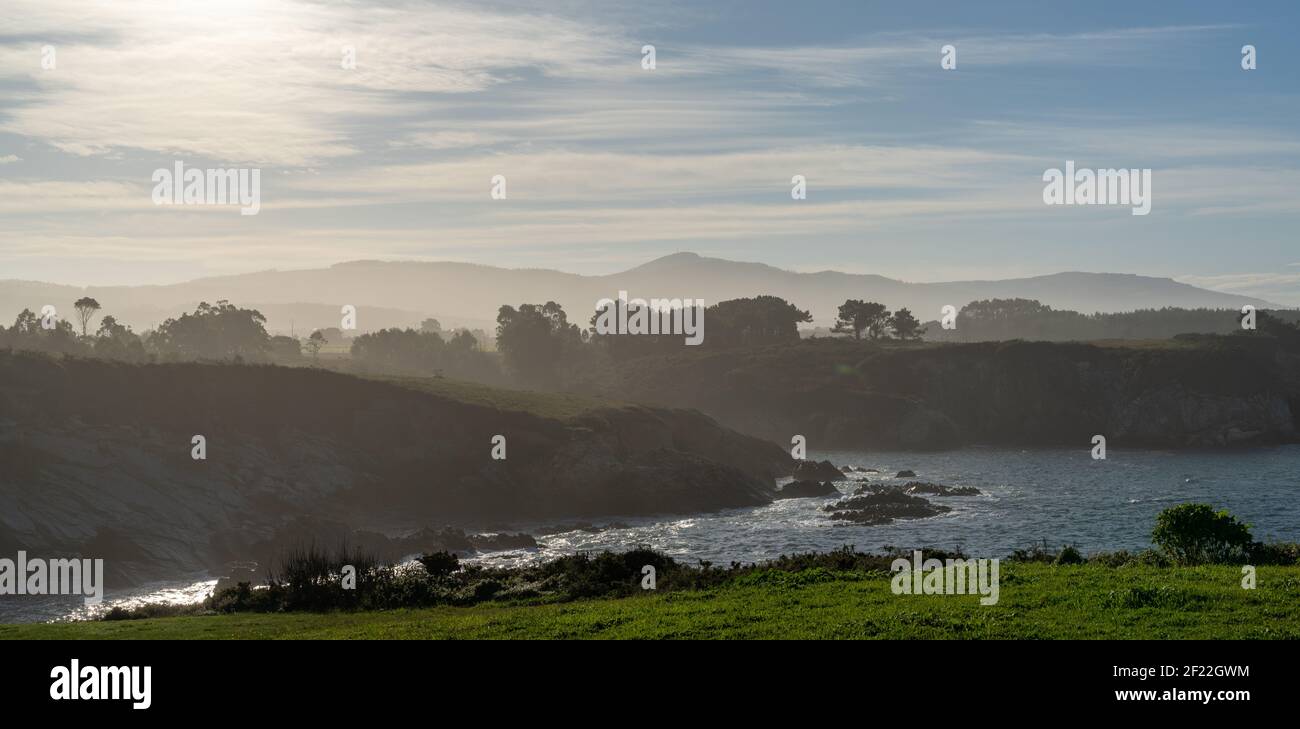 Blick auf die neblige und felsige, von Bäumen gesäumte Küste Galiciens Stockfoto