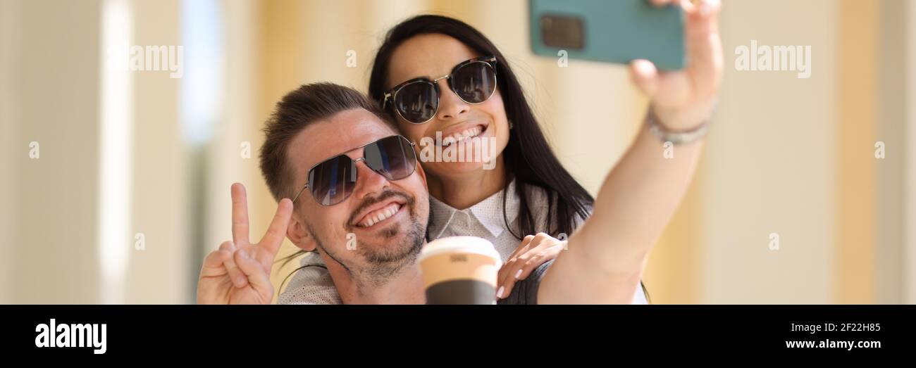 Mann und Frau in Sonnenbrillen nehmen Selfie in einem Umarmen Stockfoto