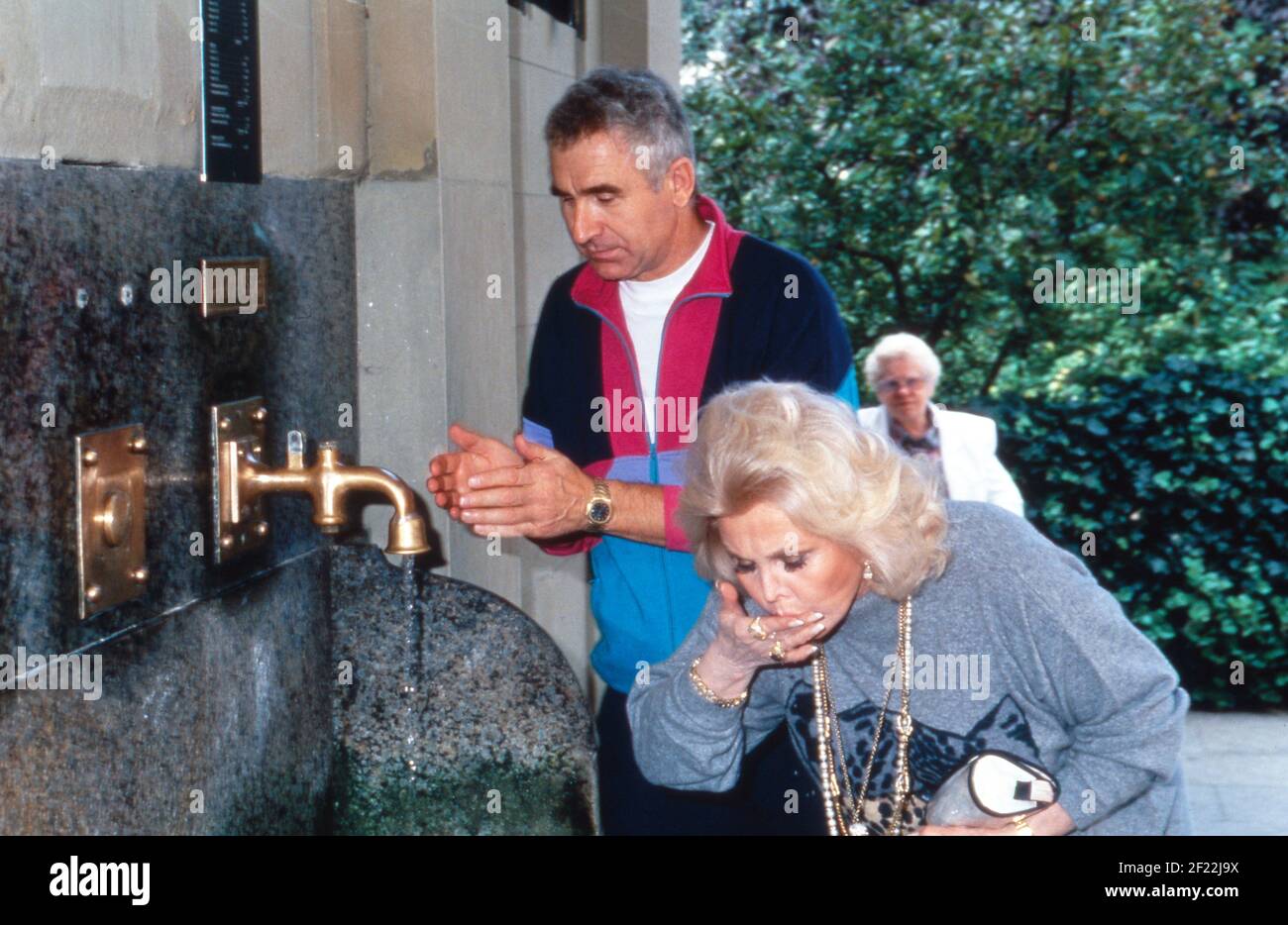 ZSA Zsa Gabor und Ehemann Frederic Prinz von Anhalt nehmen einen Schluck Heilwasser im Rahmen ihrer Aslan Therapie in Bad Kissingen, Deutschland 1992. Stockfoto