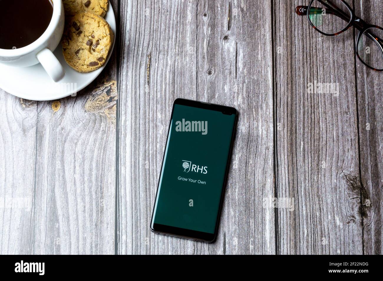 Ein Handy oder Handy auf einem Holz gelegt Tabelle mit geöffneter RHS-App auf dem Bildschirm Stockfoto