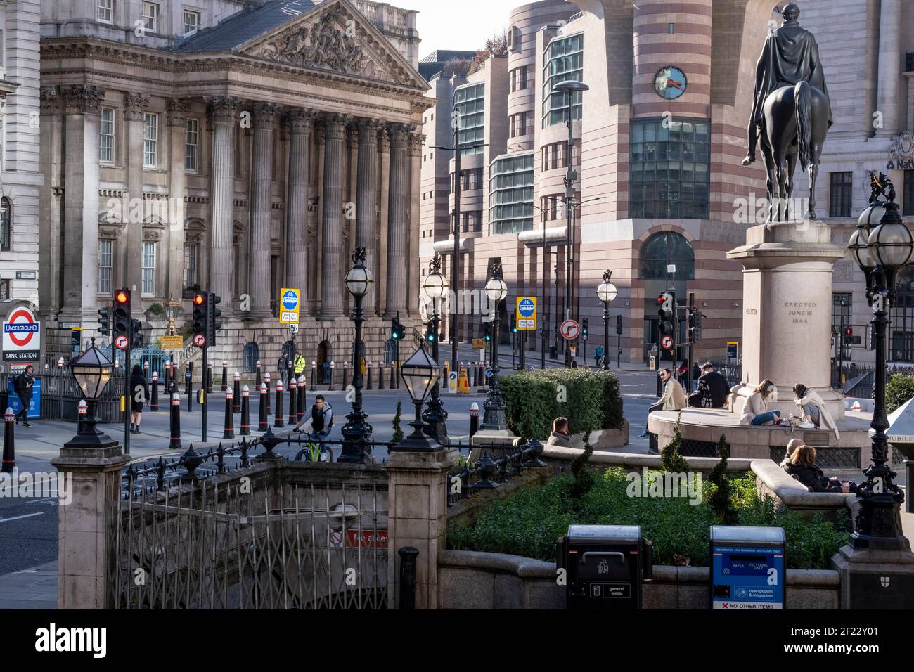 Reflektiertes Sonnenlicht beleuchtet die Bank Triangle Kreuzung während einer viel ruhigeren abendlichen Rush-Hour während der dritten Sperre der Coronavirus Pandemie. Finanzinstitute, die Statue des Duke of Wellington, das Mansion House und die Bank of England befinden sich hier, im Herzen der City of London, aka Square Mile, am 9th. März 2021, in London, England. Stockfoto