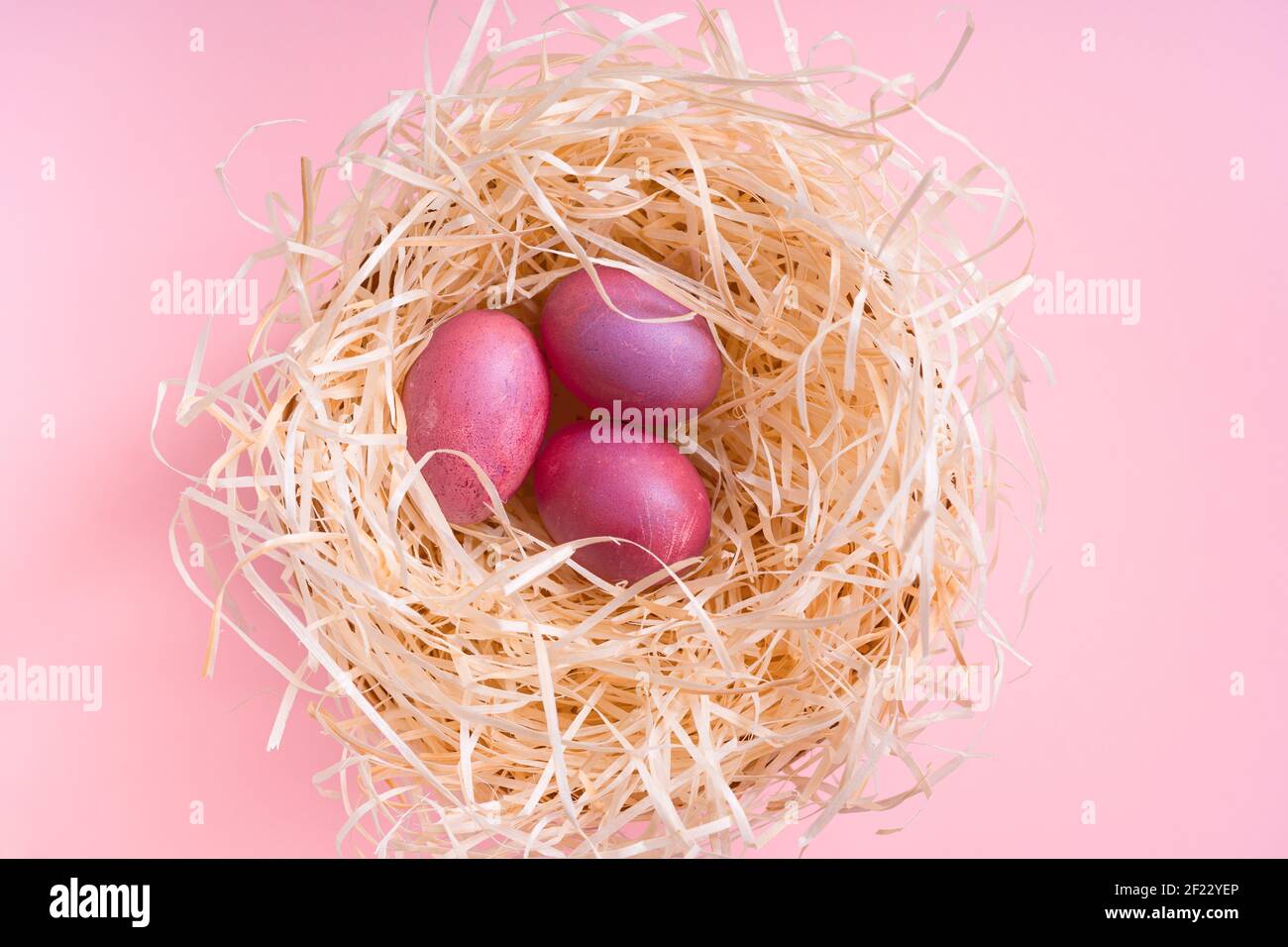 Umweltfreundliches Osterdekor mit natürlichen, wiederverwendbaren, abfallfreien Materialien, handgefertigten gefärbten Eiern, Upcycling-Geschenkpaket, Nest mit Ostereiern auf rosa Rücken Stockfoto