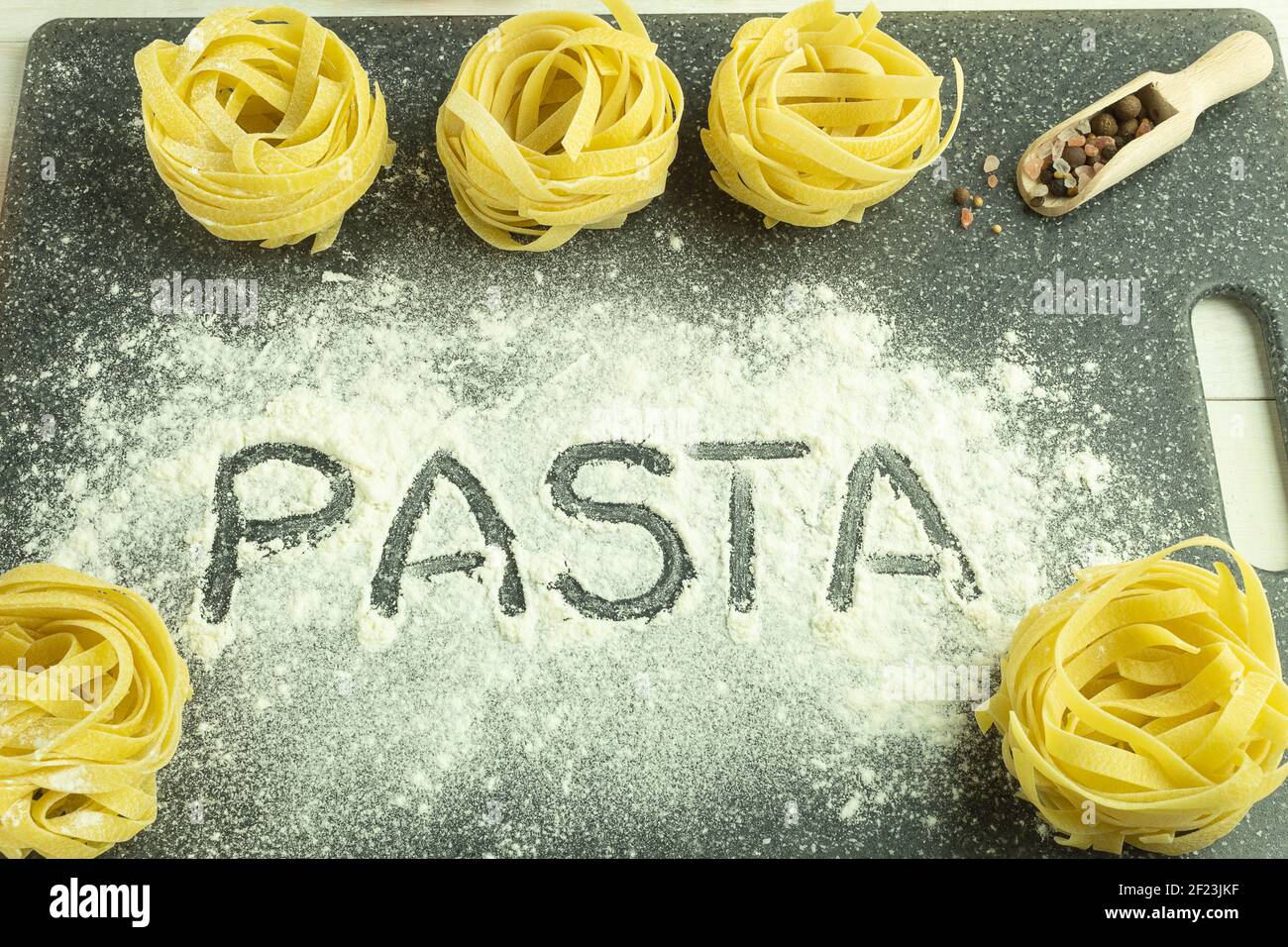 Das Wort Pasta auf einem Pasta-Hintergrund. Pasta Wort auf dem Tisch Zusammensetzung mit Zutaten geschrieben Stockfoto
