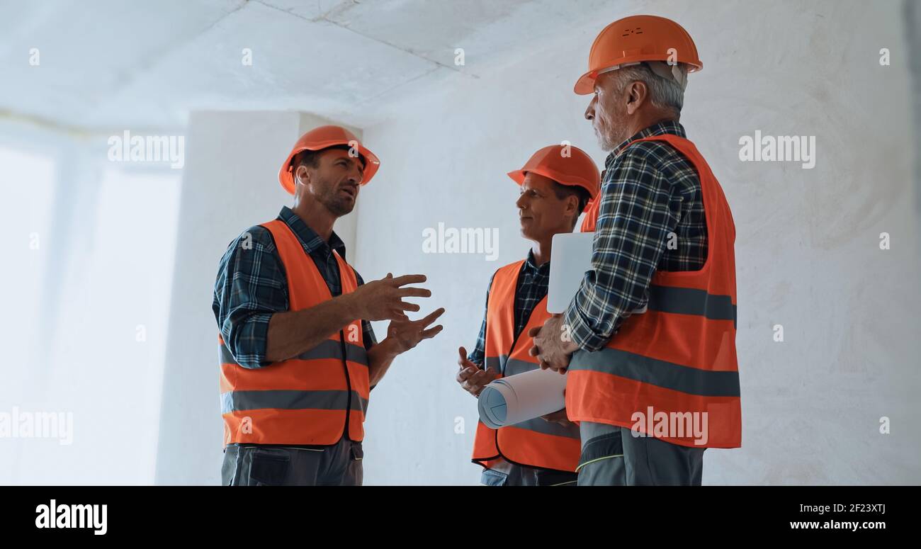 Builder gestikulieren, während im Gespräch mit Kollegen in Hartmützen auf Baustelle Stockfoto