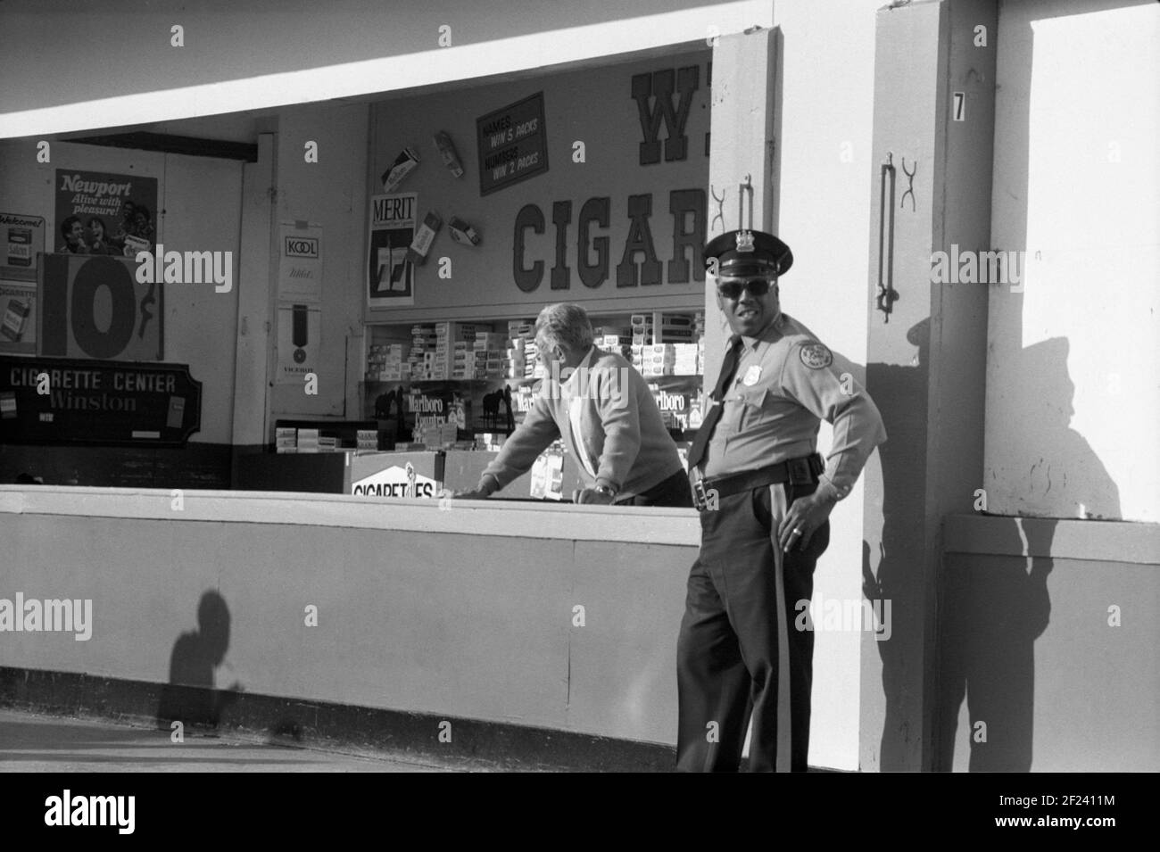 Ein Offizier steht vor einem Tabakladen. Philadelphia PA, USA, 1977 Stockfoto
