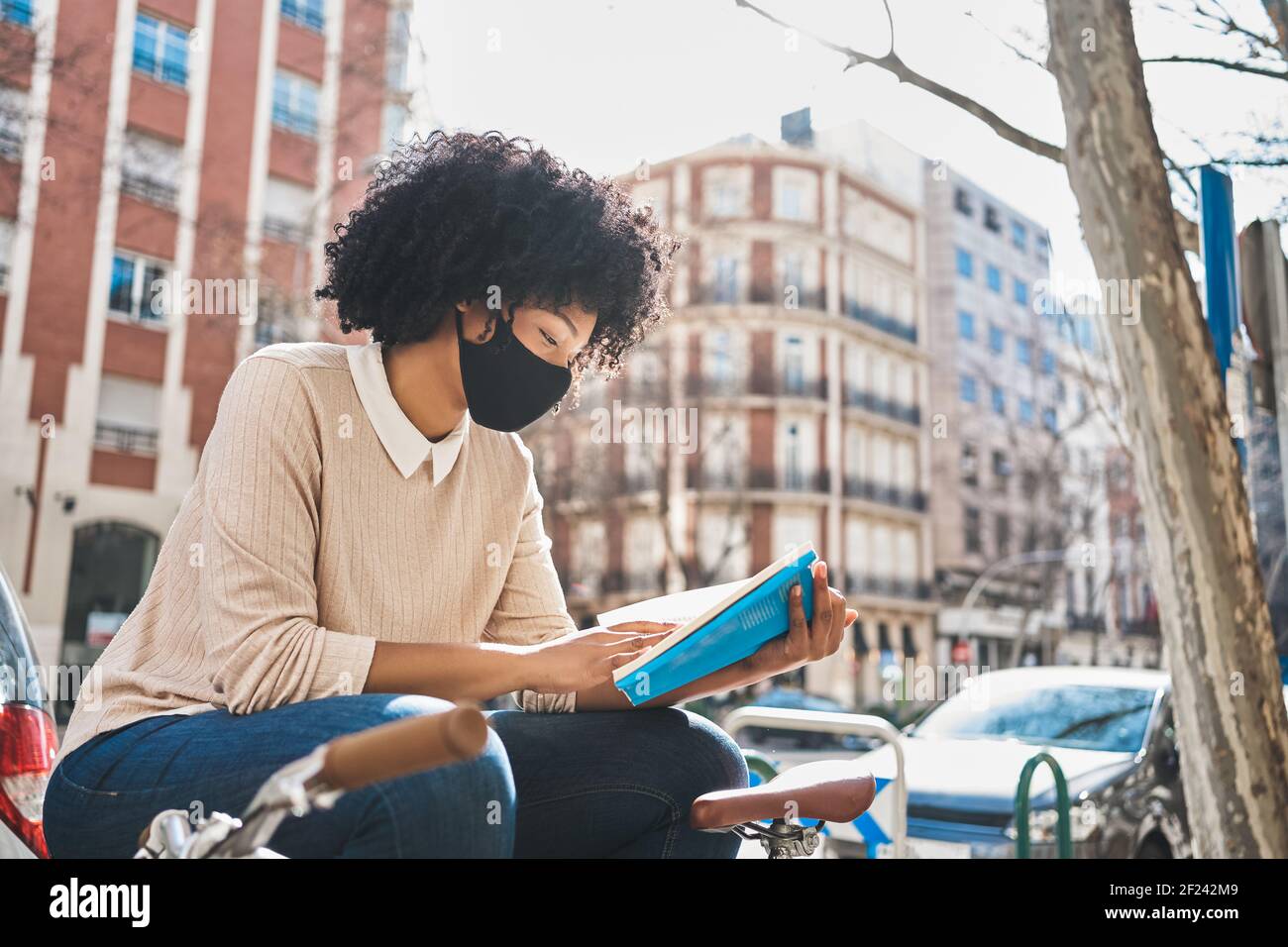 Afroamerikanische Frau, die ein Buch liest, das auf einer Bank sitzt. Latina Frau mit einem Buch. . Hochwertige Fotos Stockfoto