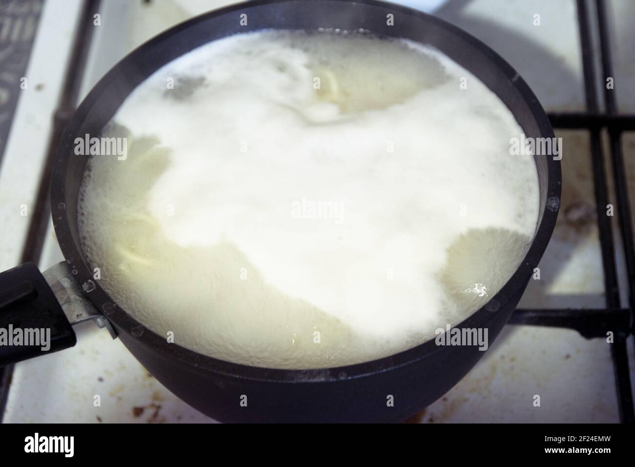 Kochendes Wasser mit Nudeln in kleinen schwarzen Kochtöpfen mit Antihaftbeschichtung. Kochen auf gebeizten Gasherd Stockfoto