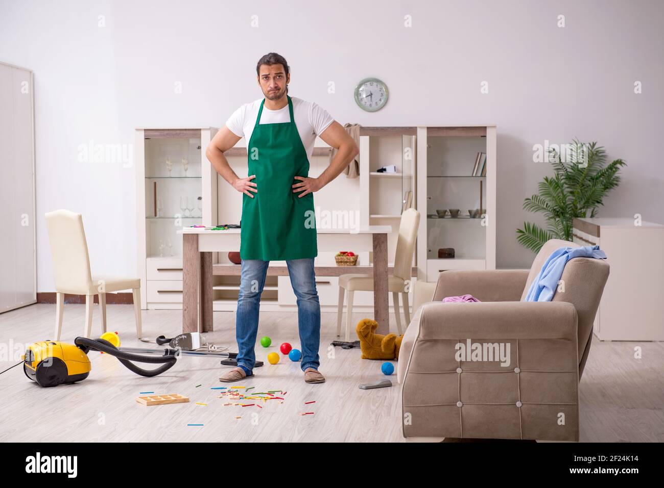 Junger männlicher Bauunternehmer, der die Wohnung nach der Kinderparty putzt Stockfoto