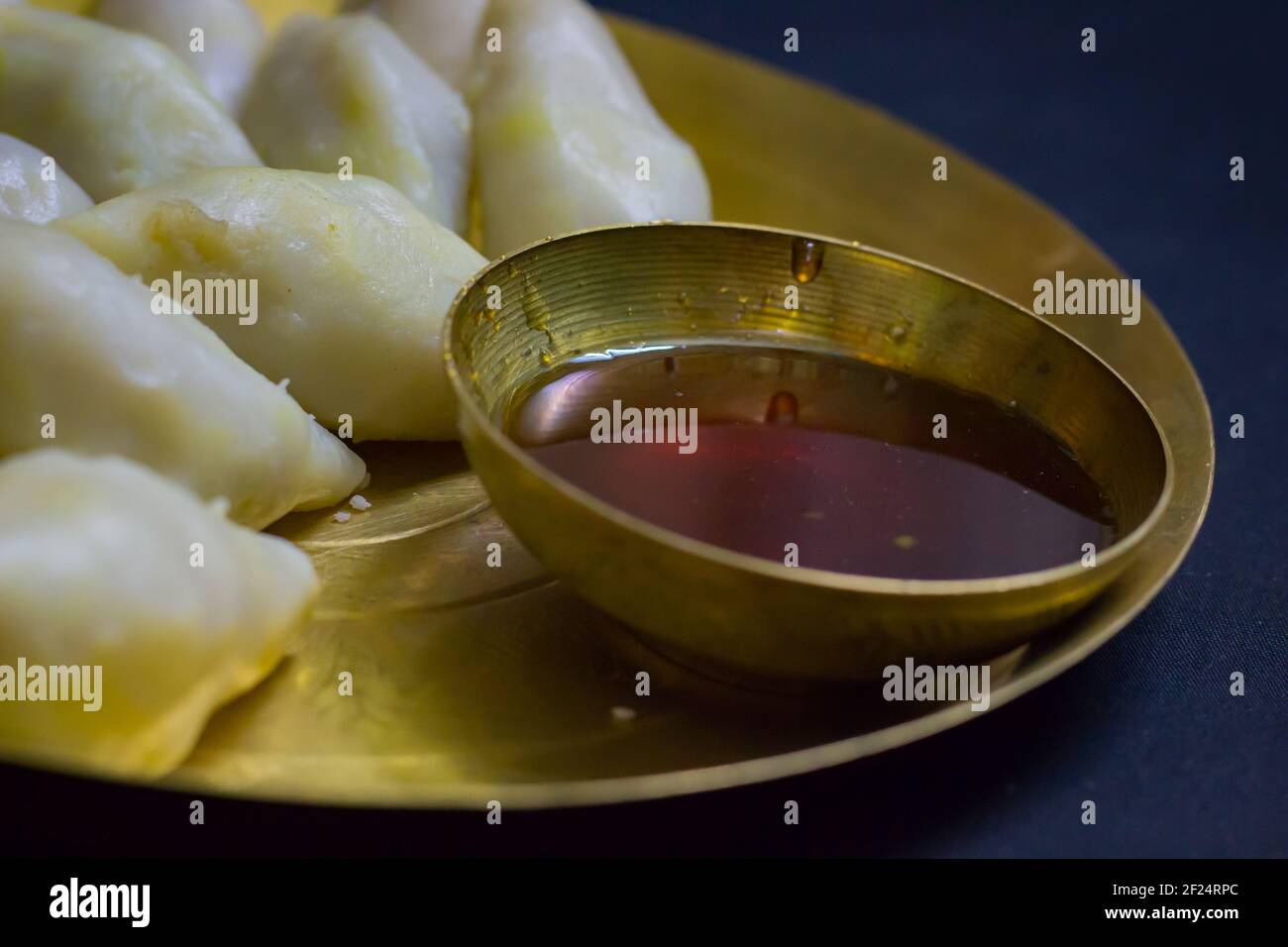 Köstliche bengalische Reismehl Kokosnussknödel serviert während bengali indian Festival von makar sankranti. Hände essen Knödel mit Dattelpalme Jaggery. Stockfoto