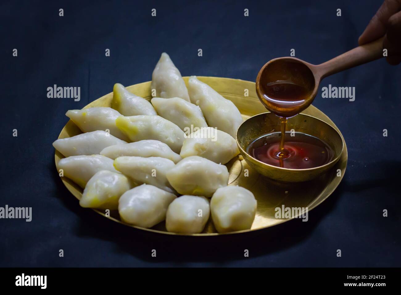 Köstliche bengalische Reismehl Kokosnussknödel serviert während bengali indian Festival von makar sankranti. Hände essen Knödel mit Dattelpalme Jaggery. Stockfoto