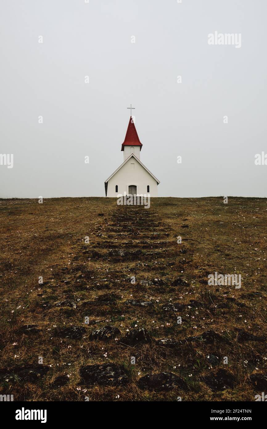 Die kleine Breidavik Kirche und Schritte in der düsteren tief Wolke Island Landschaft der Westfjorde - island Minimalismus Stockfoto