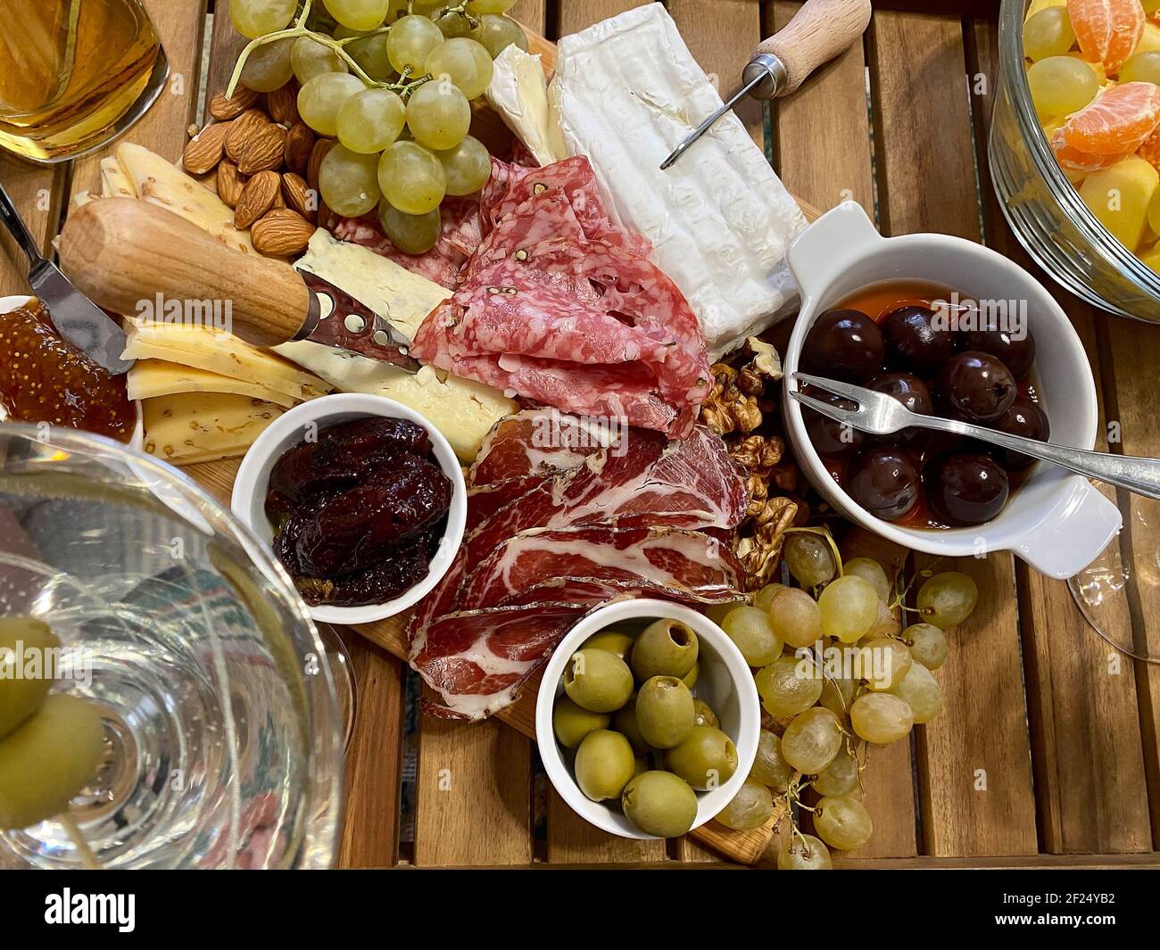 Kaltes Fleisch und verschiedene Käsesorten, Oliven, eingelegte Trauben auf einem Holzbrett. Weinsnack, Käseplatte Stockfoto