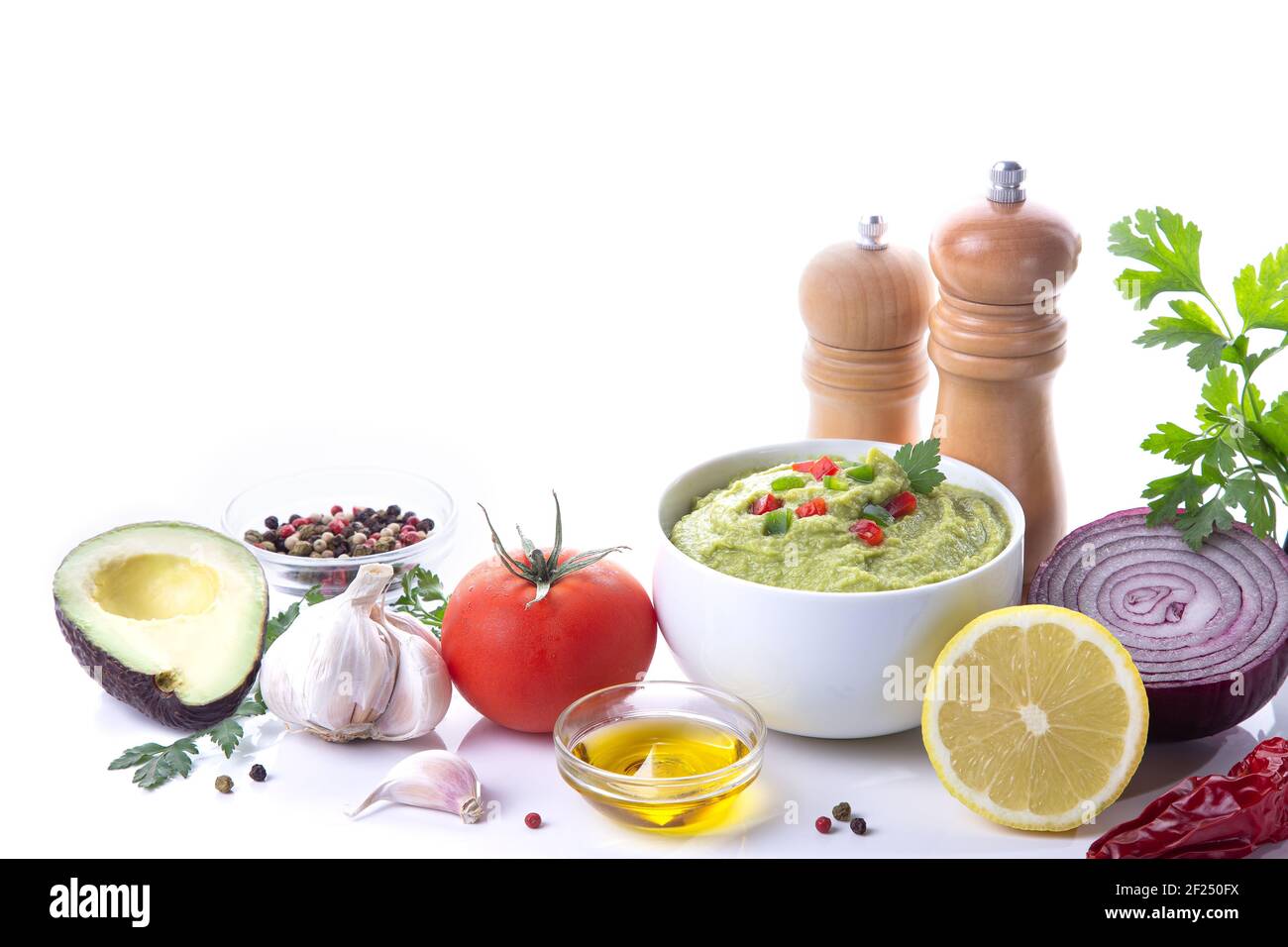 Schüssel mit Guacamole und Zutaten auf weißem Hintergrund mit Kopierraum. Stockfoto