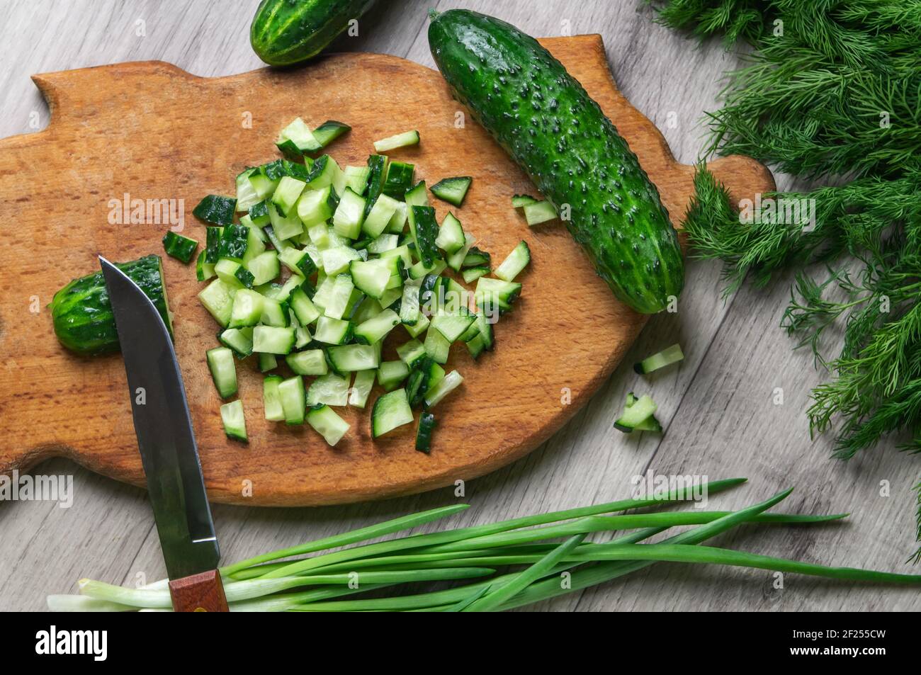 Frische Gurke, fein gehackt auf einem alten Holzschneidebrett. Zutat für Salat. Home Food-Konzept. Natürliche Lebensmittel. Stockfoto