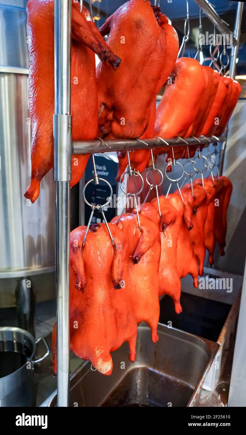 Eingelegte Entenkadaver, die an Haken hängen, zum Braten vorbereitet. Wiederherstellung des Geschäfts. Pekingente. Chinesische Küche. Stockfoto