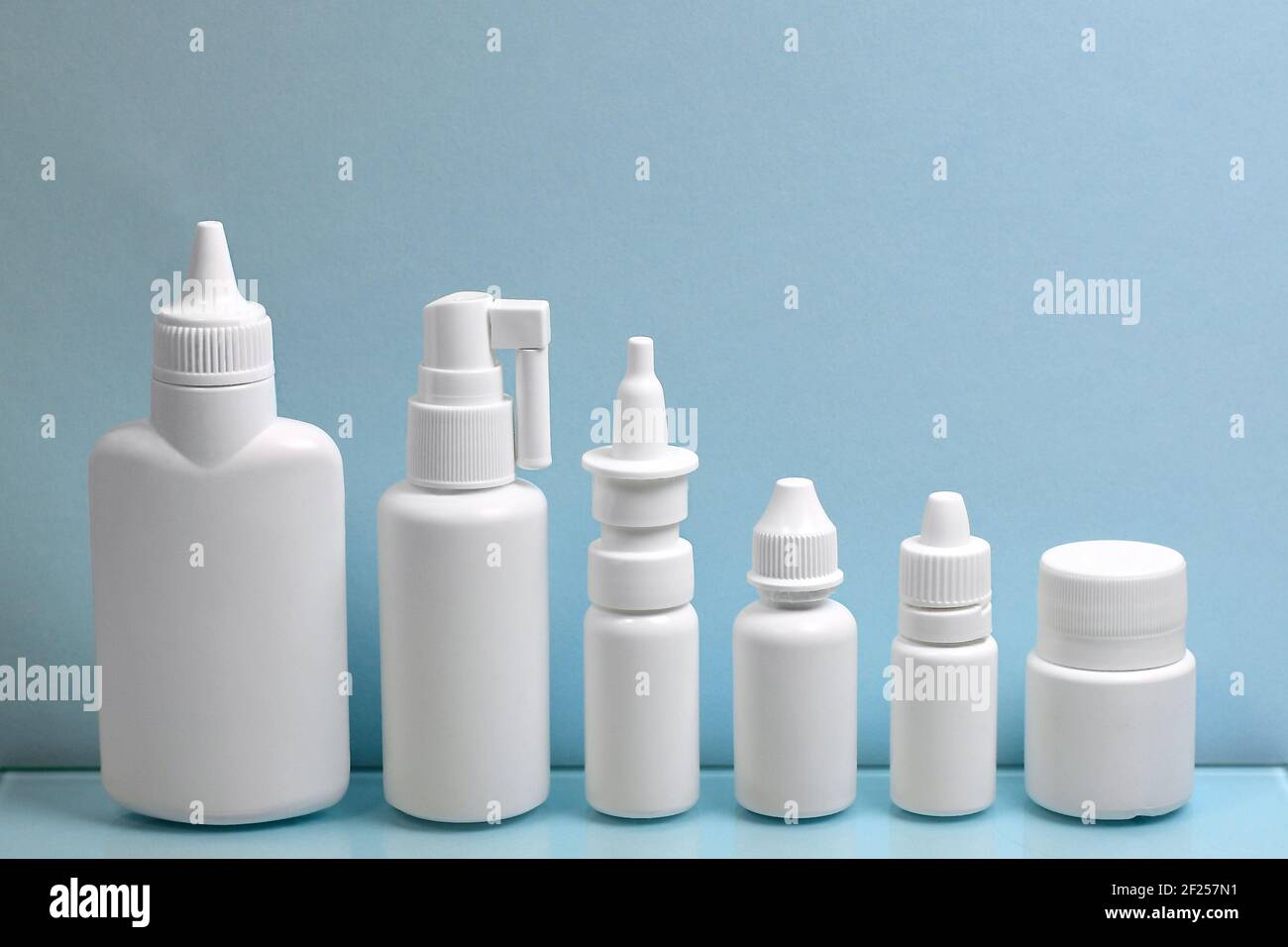 Ein vielfältiges Set aus weißen Kunststoffbehältern für Pharmazeutika, aufgereiht in der Reihenfolge der Größe in der Höhe. Auf hellblauem Hintergrund. Stockfoto